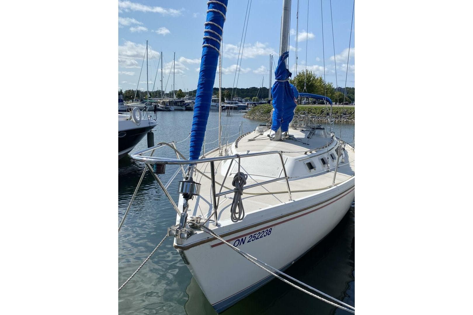 1986 Catalina 34 sailboat docked in a marina under a clear blue sky.