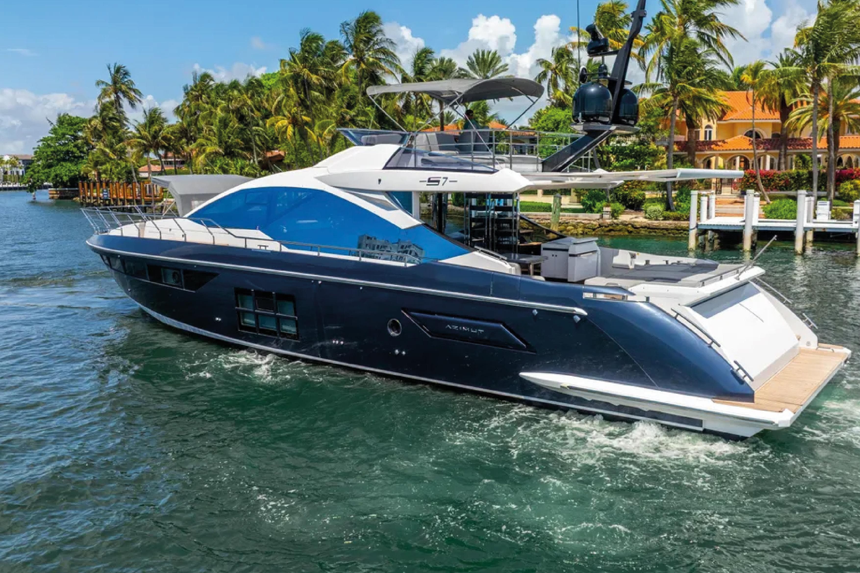 Luxurious 2019 Azimut S7 yacht cruising near tropical shoreline with palm trees.