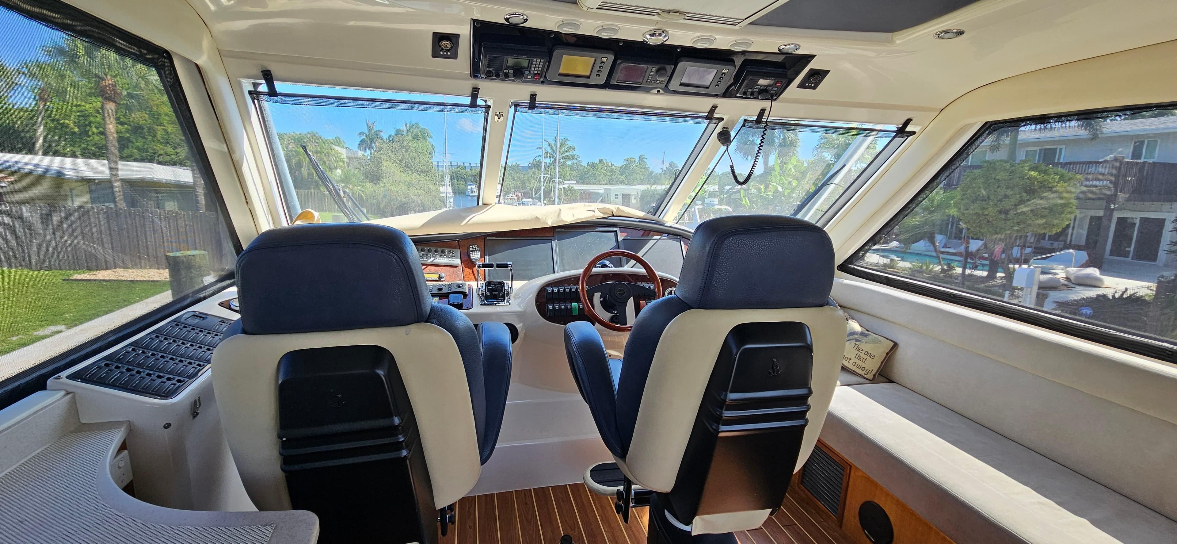 Interior view of 2004 Riviera 58 Enclosed Flybridge yacht cockpit with dual seats and panoramic windows.