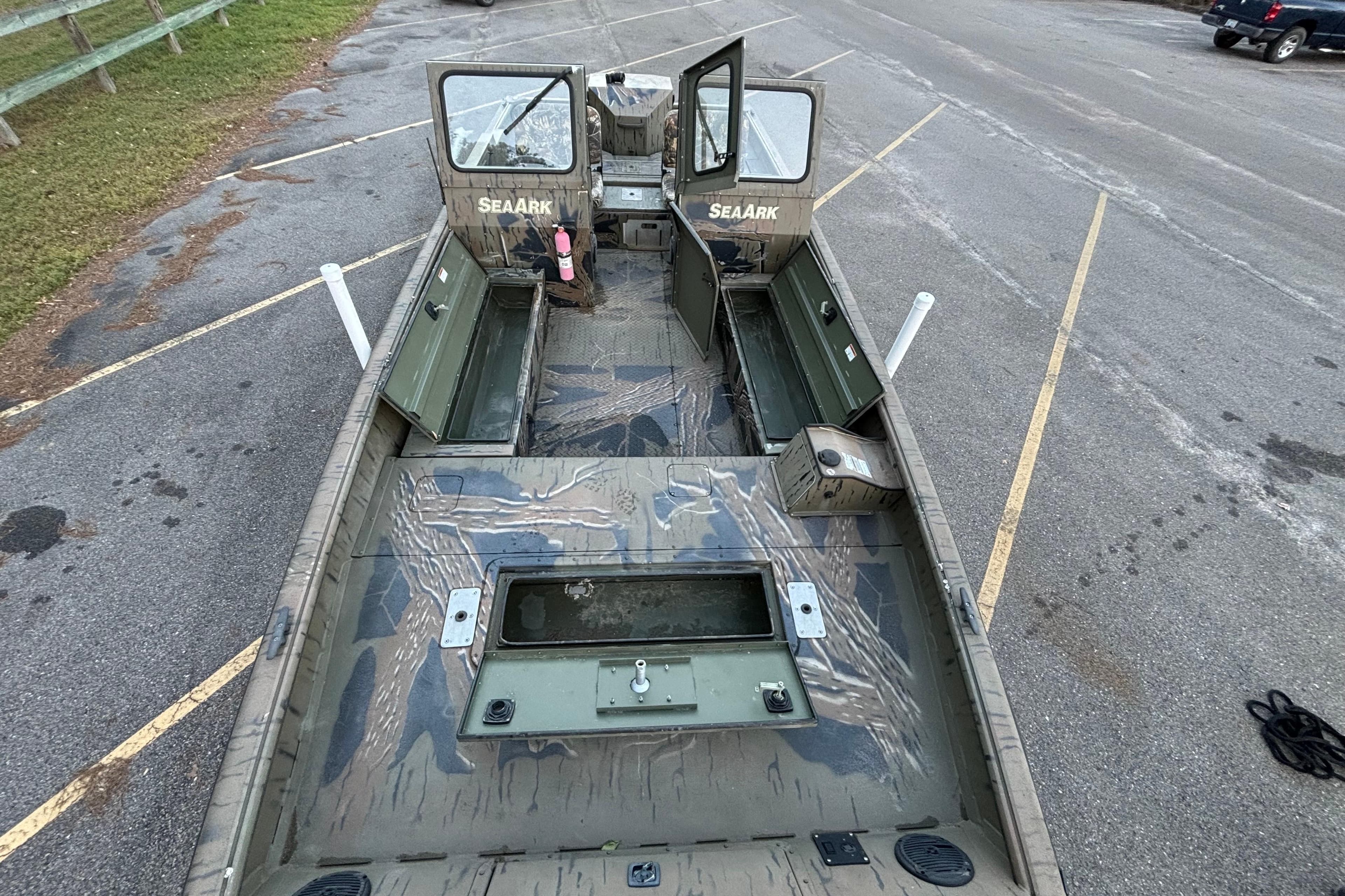 2019 SeaArk Predator 220 AK SC boat with open deck and camouflage design in a parking lot.