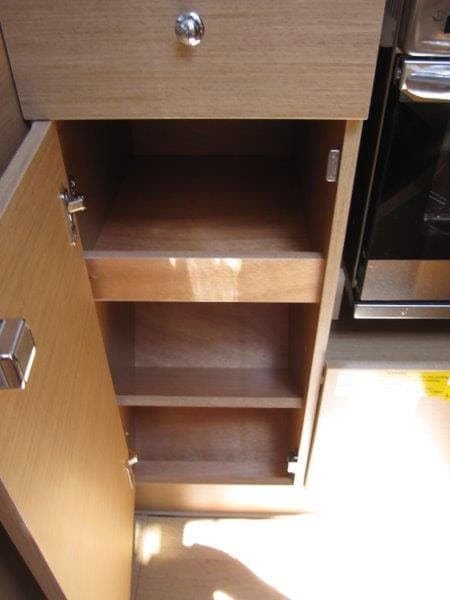 Interior cabinet of 2025 Jeanneau Sun Odyssey 350 sailboat, featuring wooden shelves.
