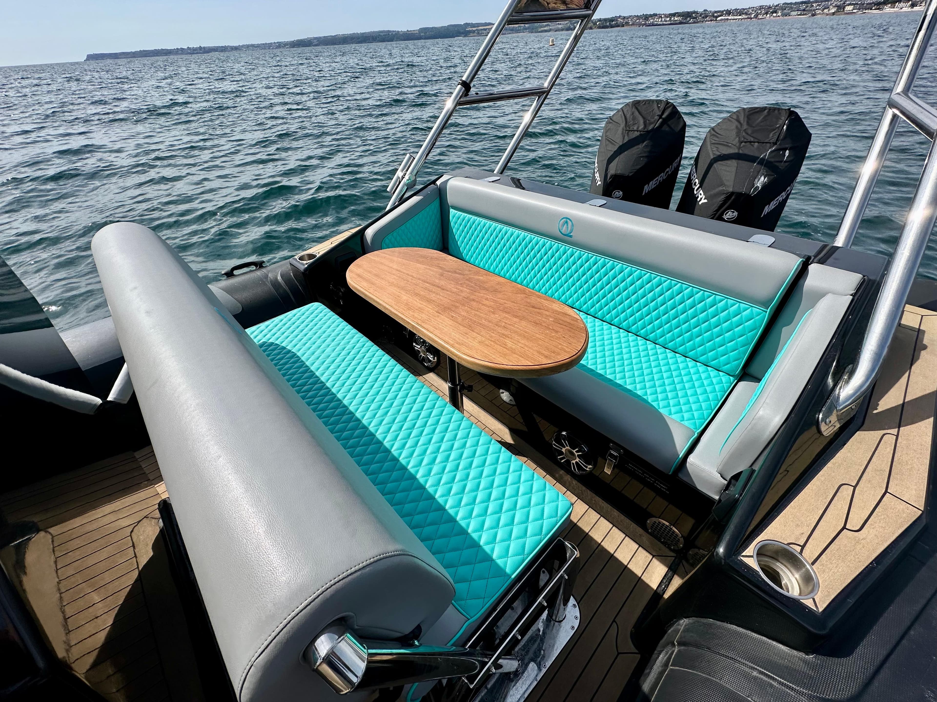 2021 Ribquest Explorer boat interior with turquoise seating and wooden table on open water.