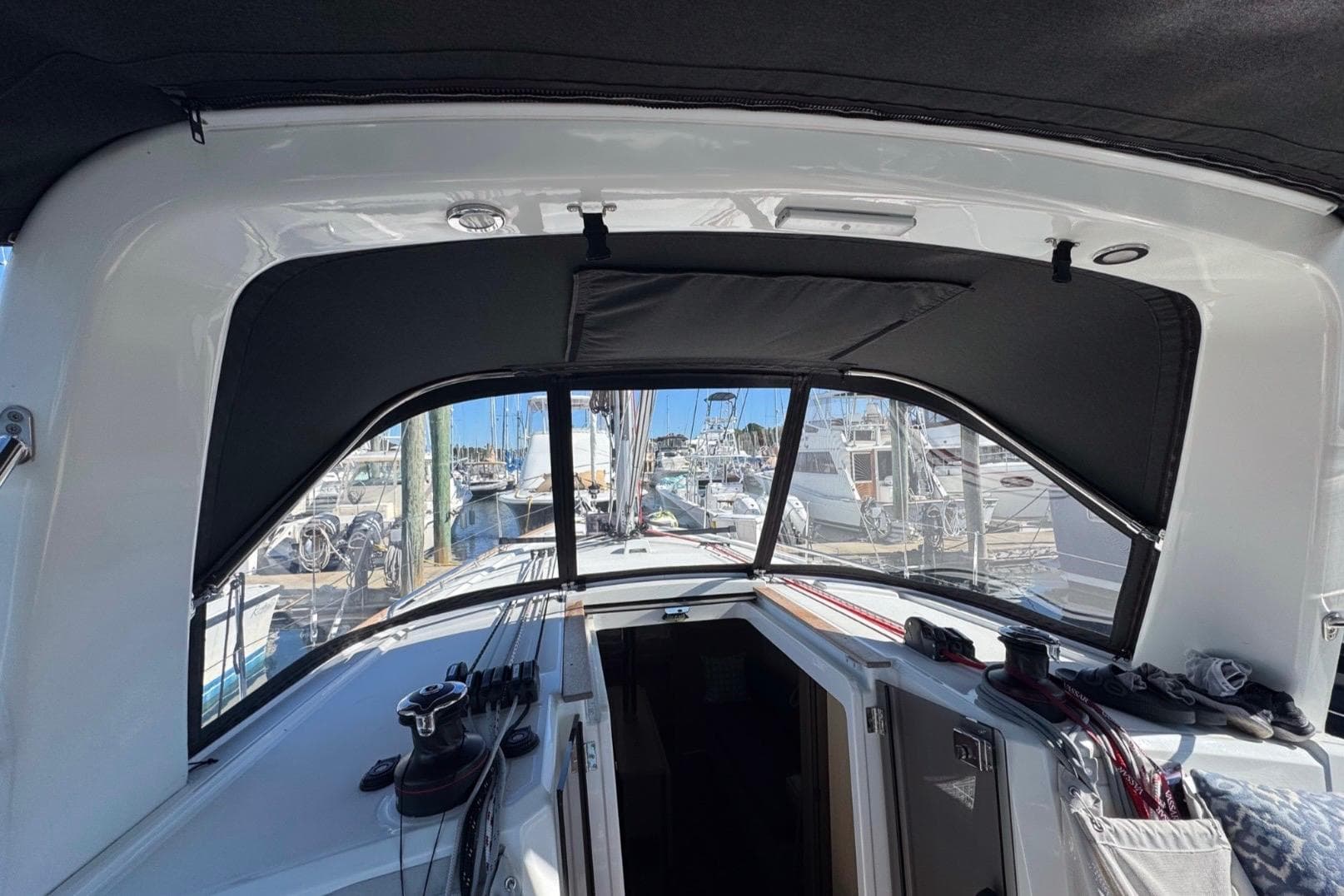 Interior view of 2023 Beneteau Oceanis 38.1 sailboat cockpit with marina background.
