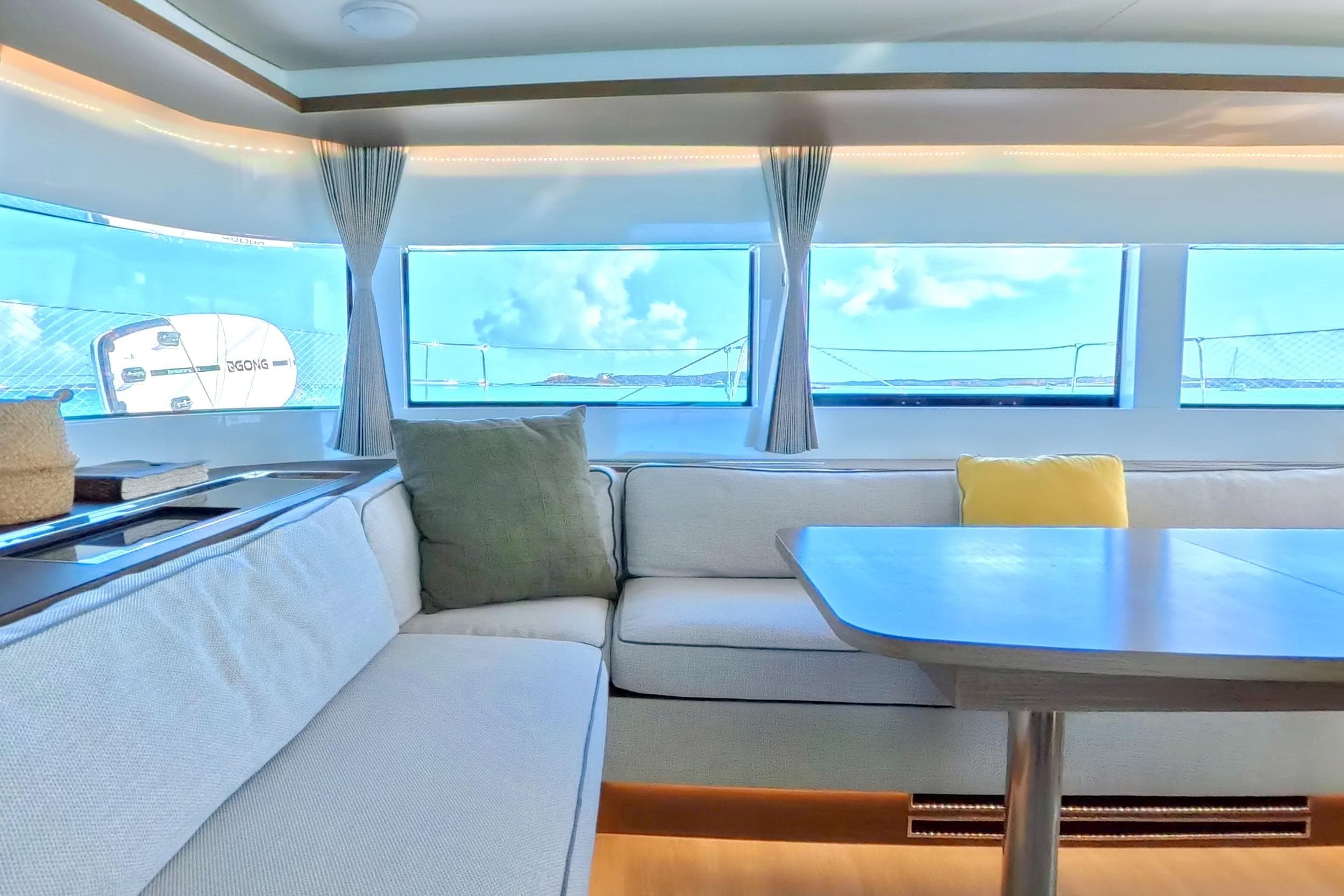 Interior of 2023 Lagoon 50 yacht with modern seating and ocean view.
