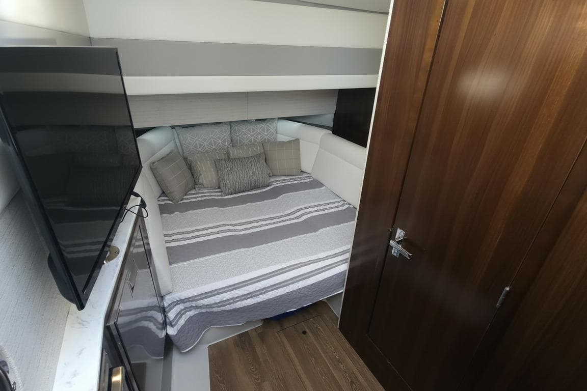 2021 Cruisers Yachts 42 GLS OB cabin interior with bed, TV, and wooden door.