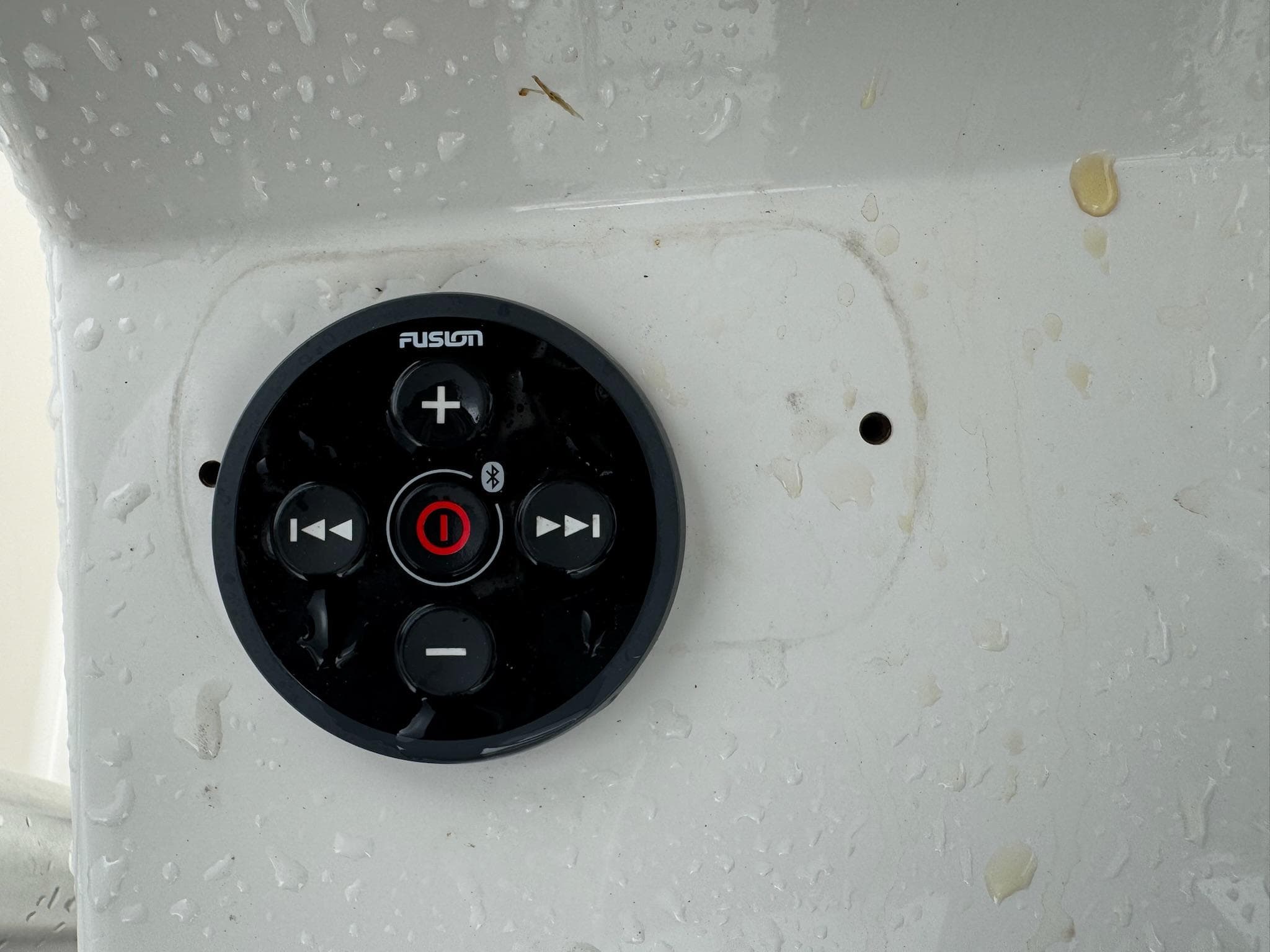Fusion audio control panel on a 2004 Robalo R230 Center Console boat, wet surface.