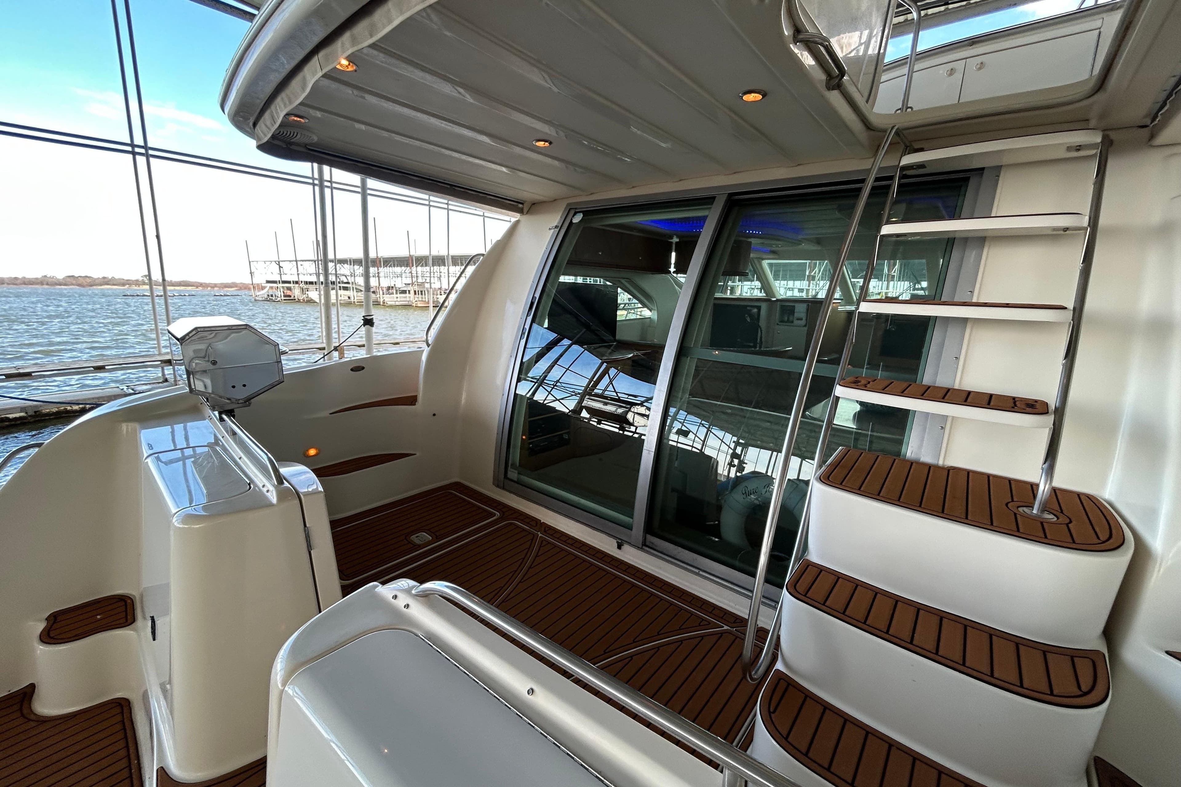 1999 Maxum 4600 SCB yacht interior with wooden steps and glass doors, docked by the water.
