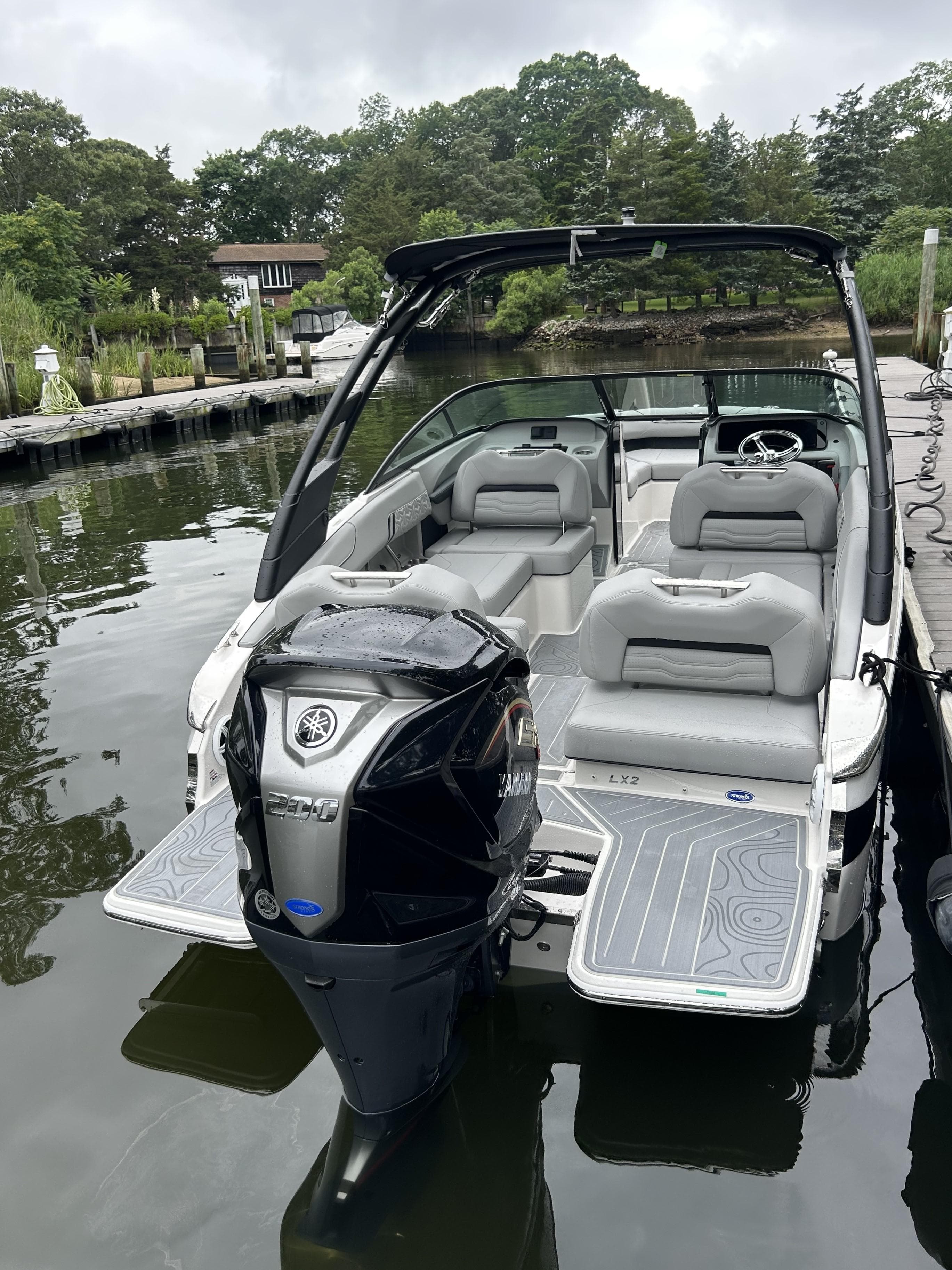 2026 Regal LX2 boat with Yamaha engine docked on a calm lake.