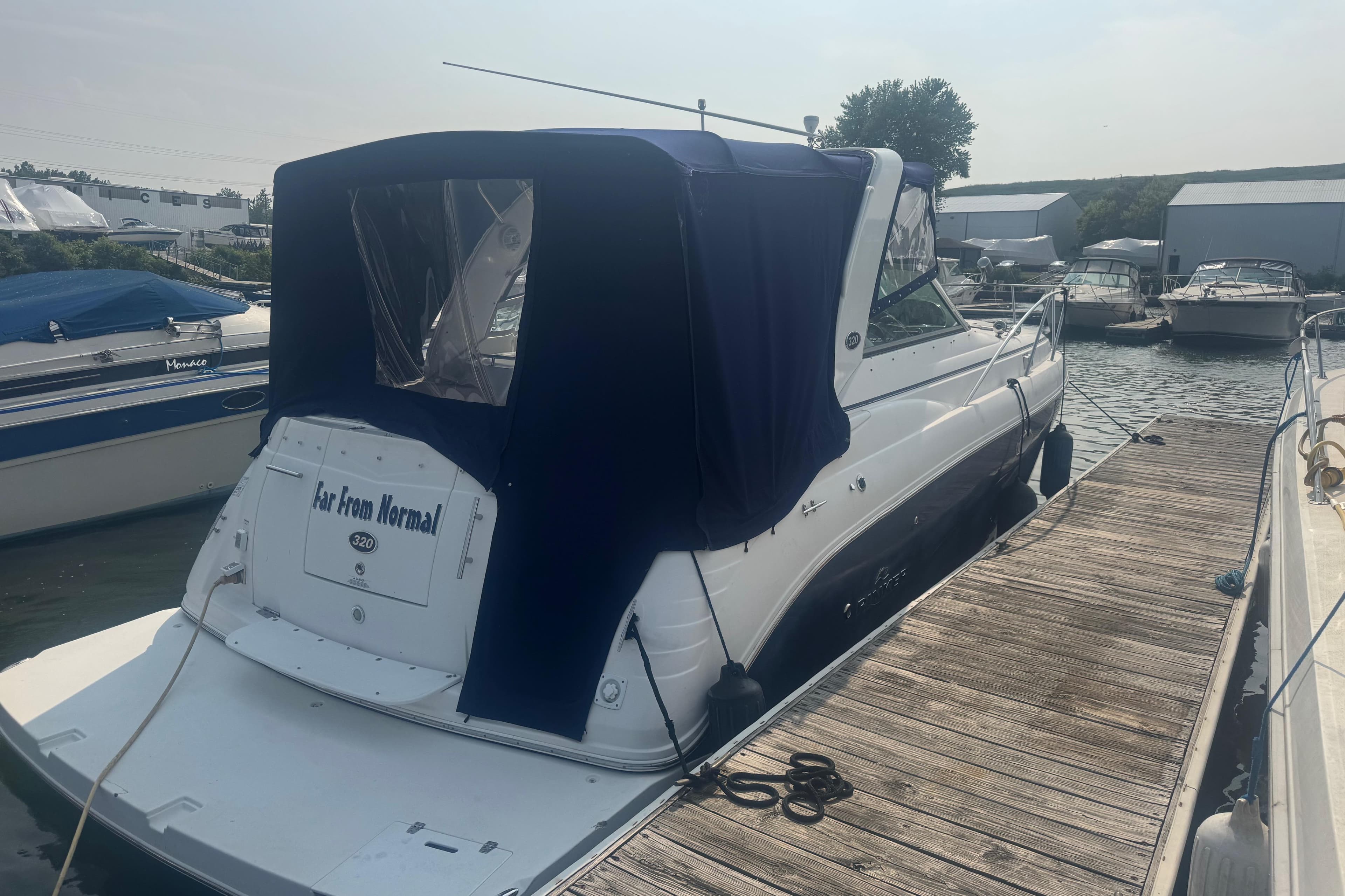 2007 Rinker 320 Express Cruiser docked with blue canopy, rear view.
