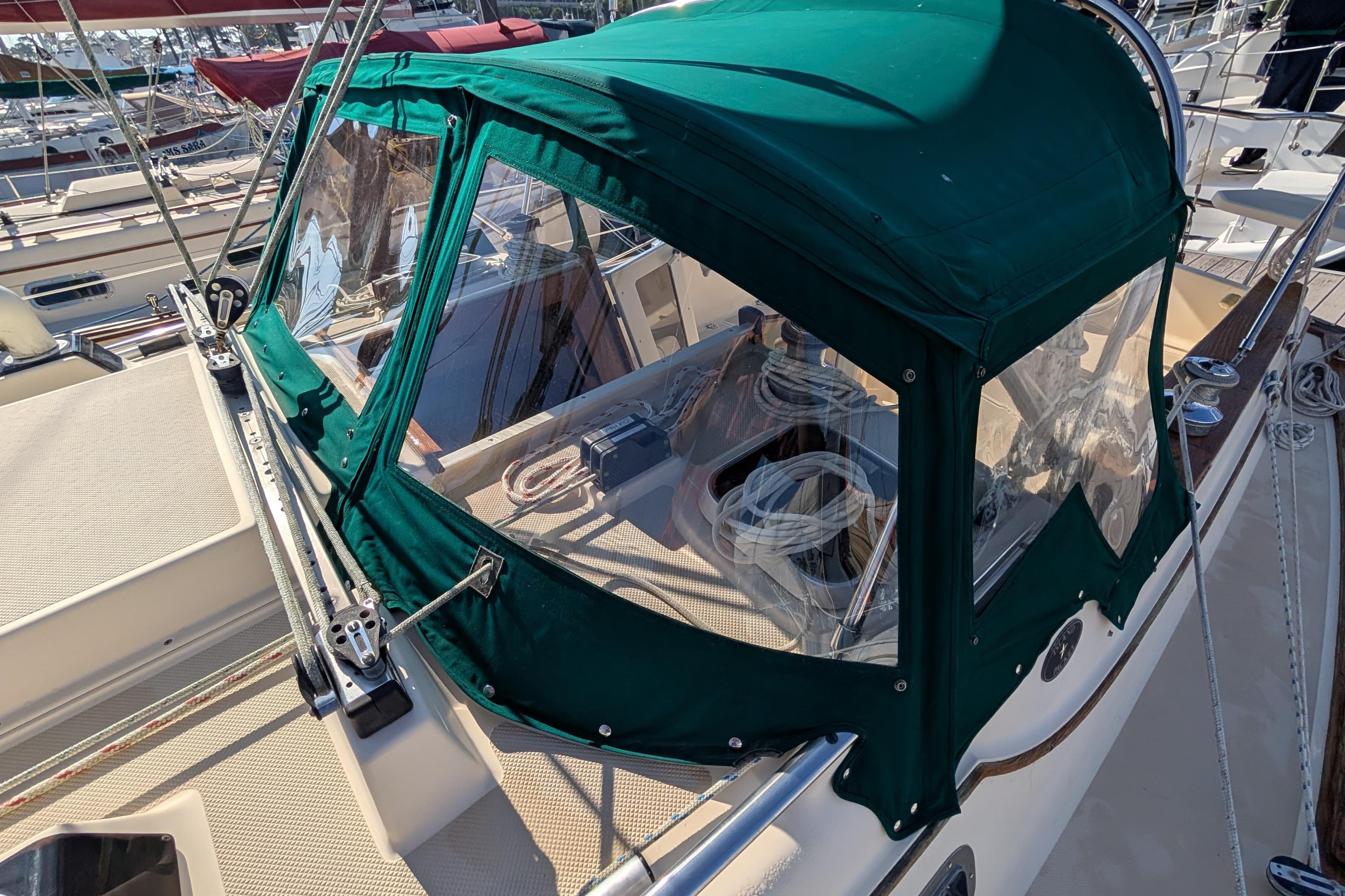 1999 Island Packet 320 sailboat with green canvas cover at marina.