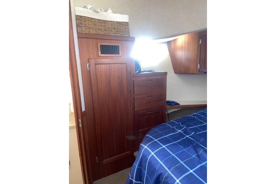 Cozy cabin interior of 2006 Nordic Tug 42 with wooden cabinetry and blue bedding.