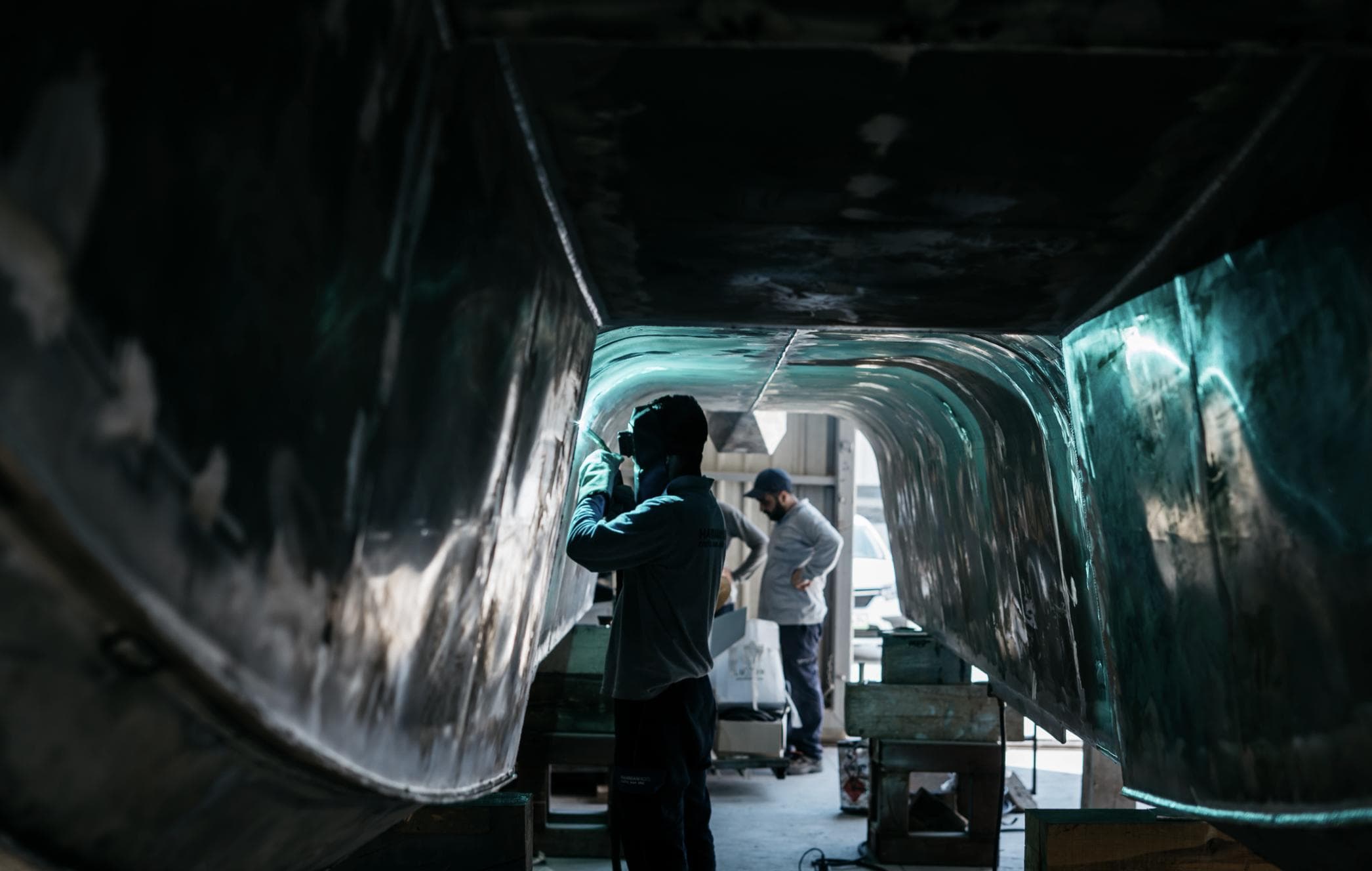 Workers inspecting the hull of a 2026 Bering Marine 34 Cabin boat.