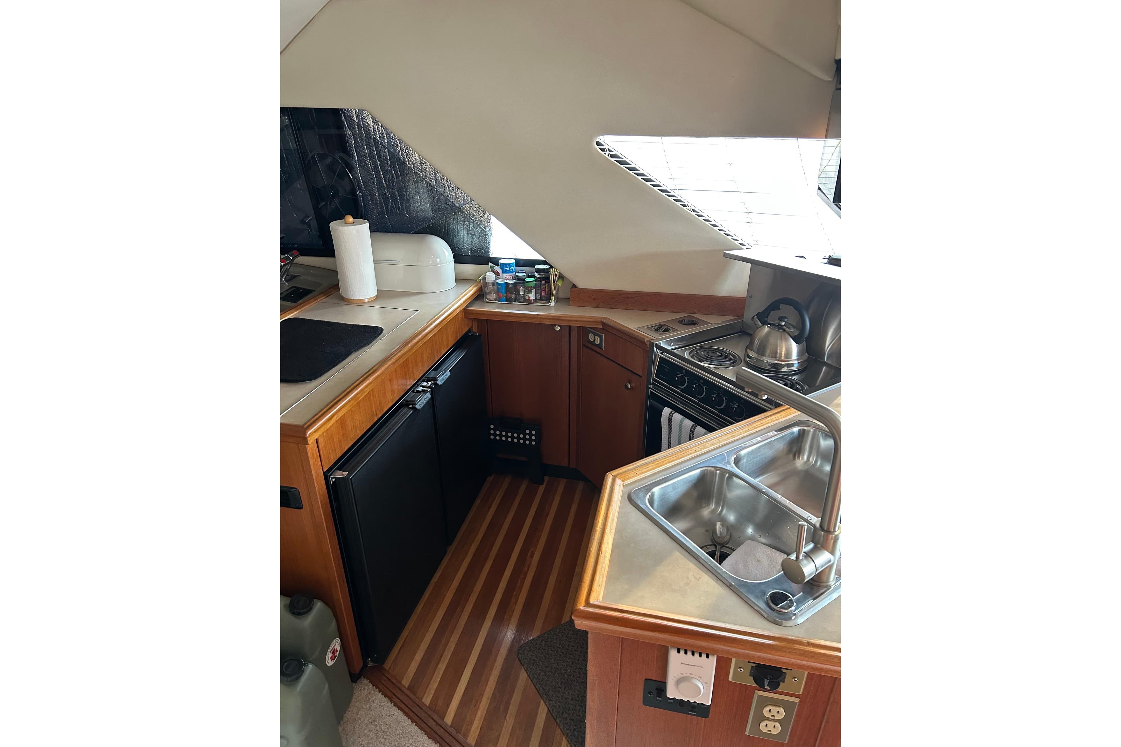 1995 Bayliner 3988 Motoryacht kitchen with stove, sink, and wooden cabinetry.