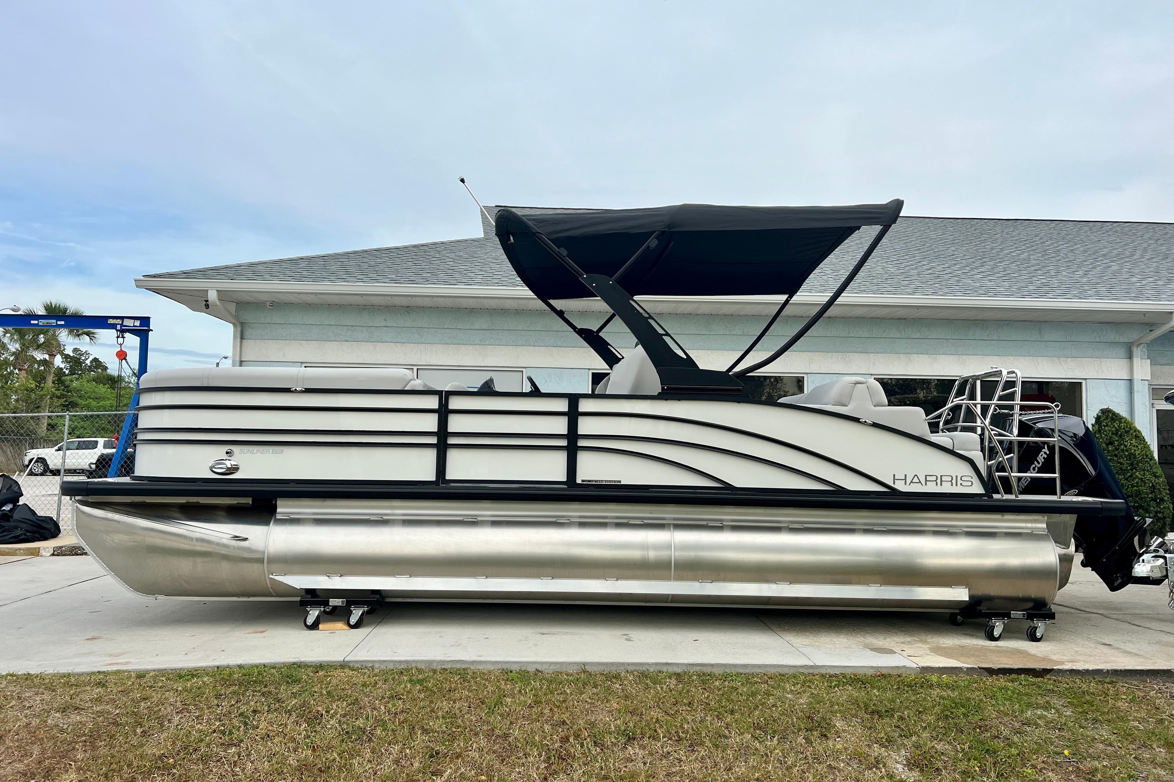 2025 Harris Sunliner 230 pontoon boat parked outside a building.