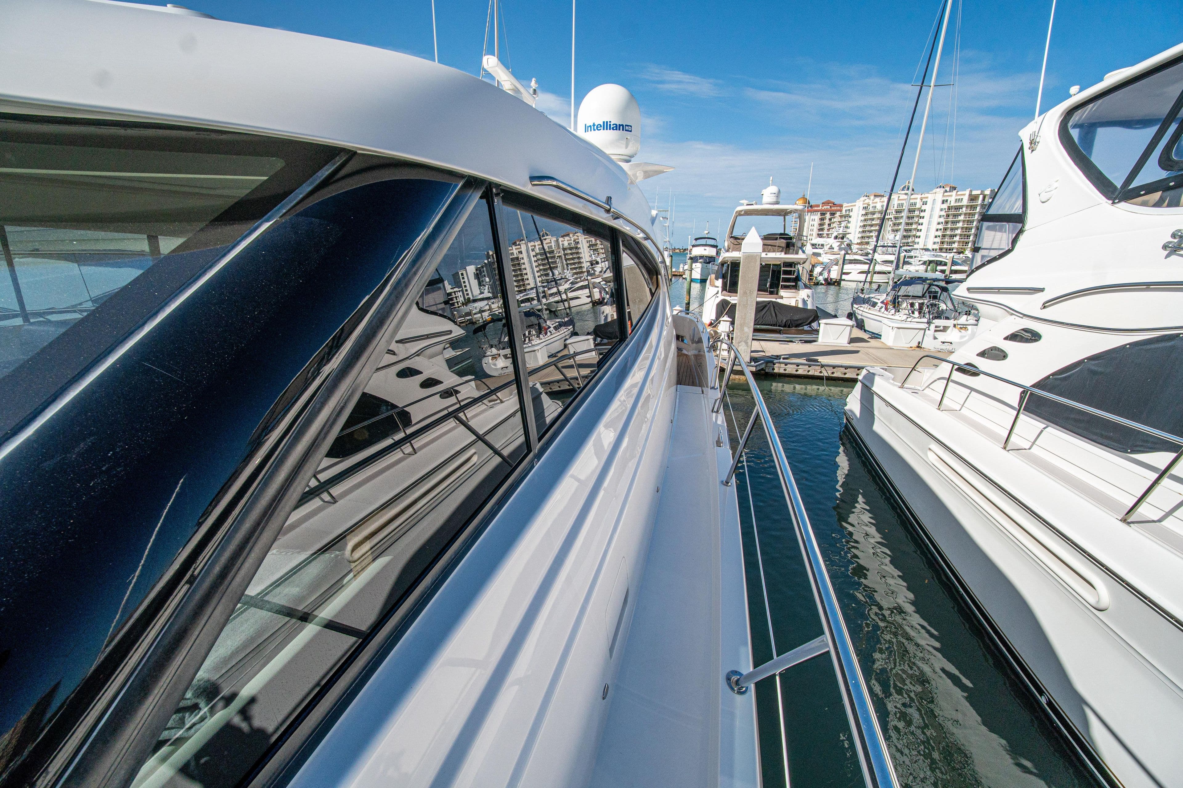 2015 Riviera 6000 Sport Yacht docked at marina, reflecting clear blue sky and nearby boats.