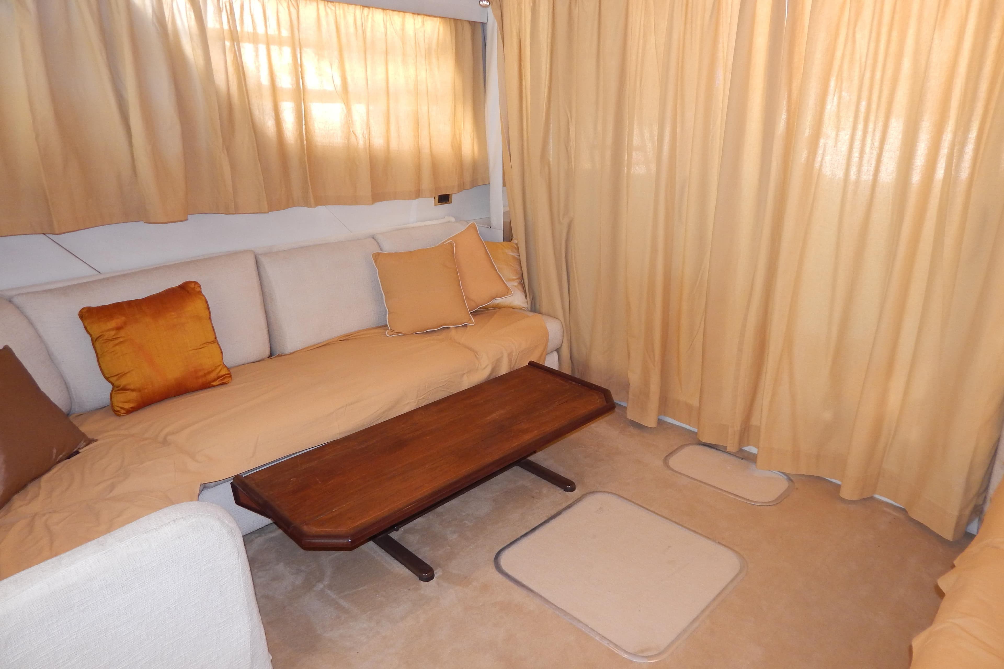 Cozy interior of 1992 Fairline 50 yacht with beige curtains and cushions.