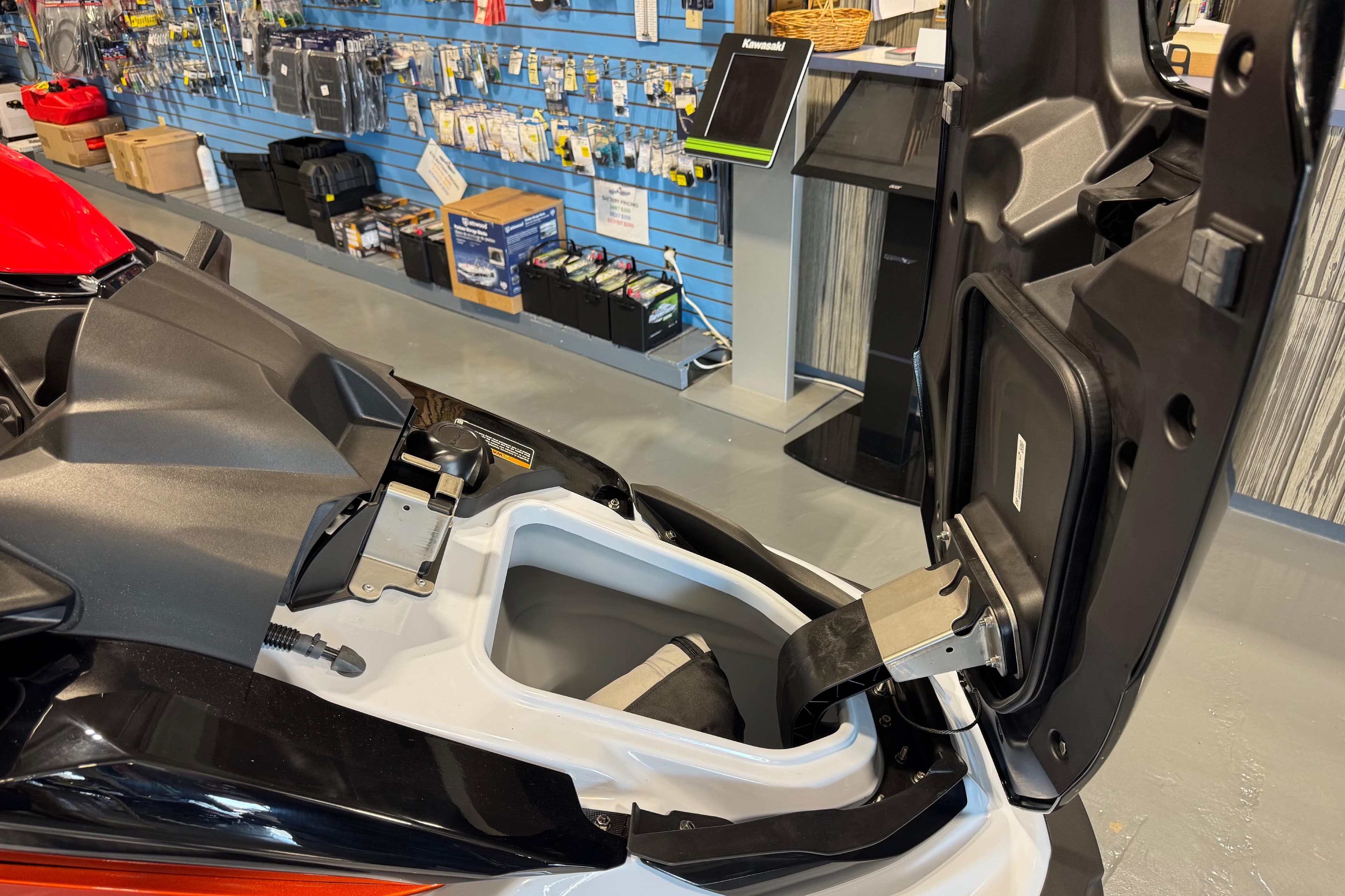 2025 Kawasaki STX160X jet ski with open storage compartment in showroom.