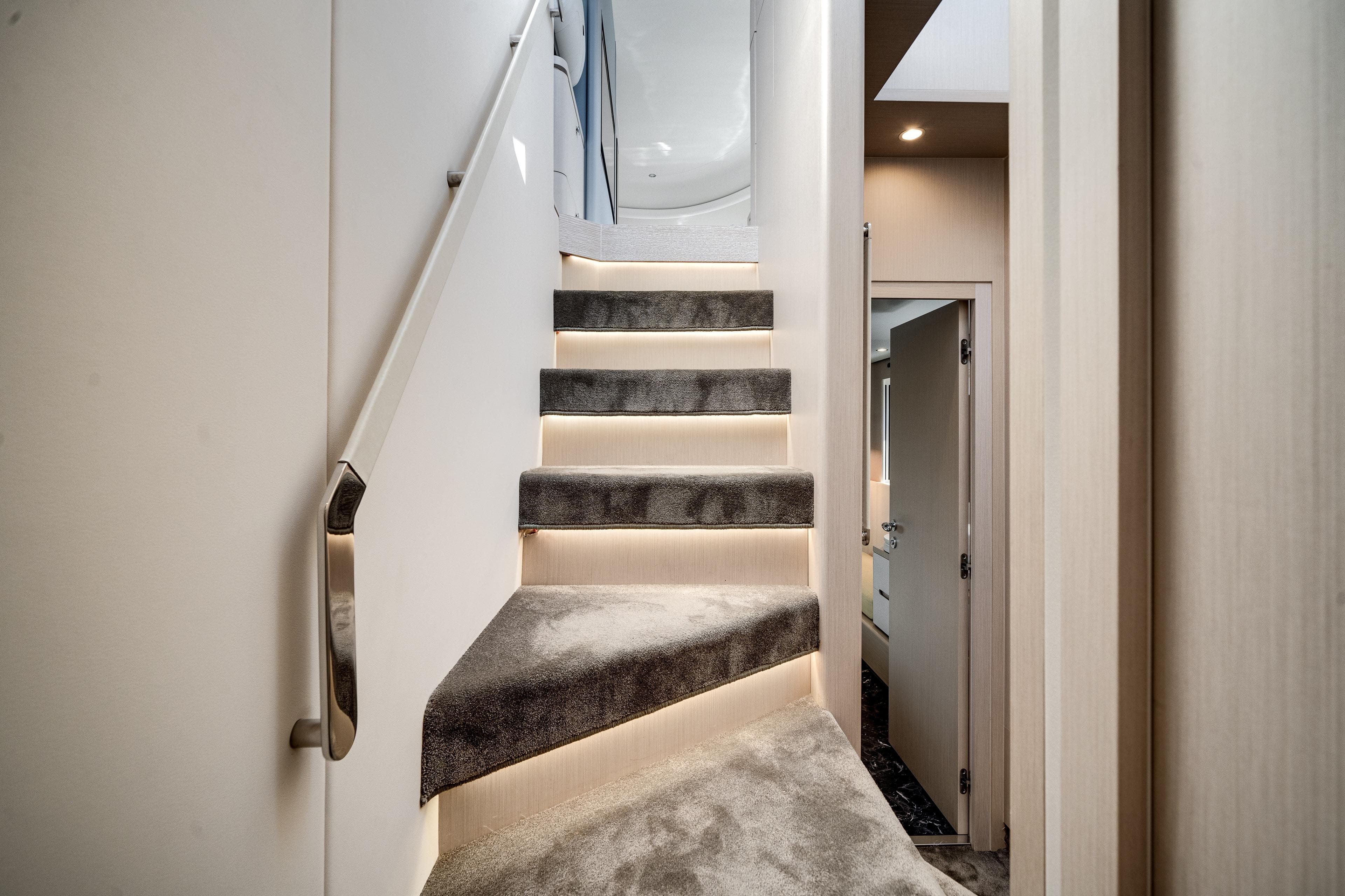Luxurious interior staircase of 2023 Azimut Fly 68 yacht with modern lighting.