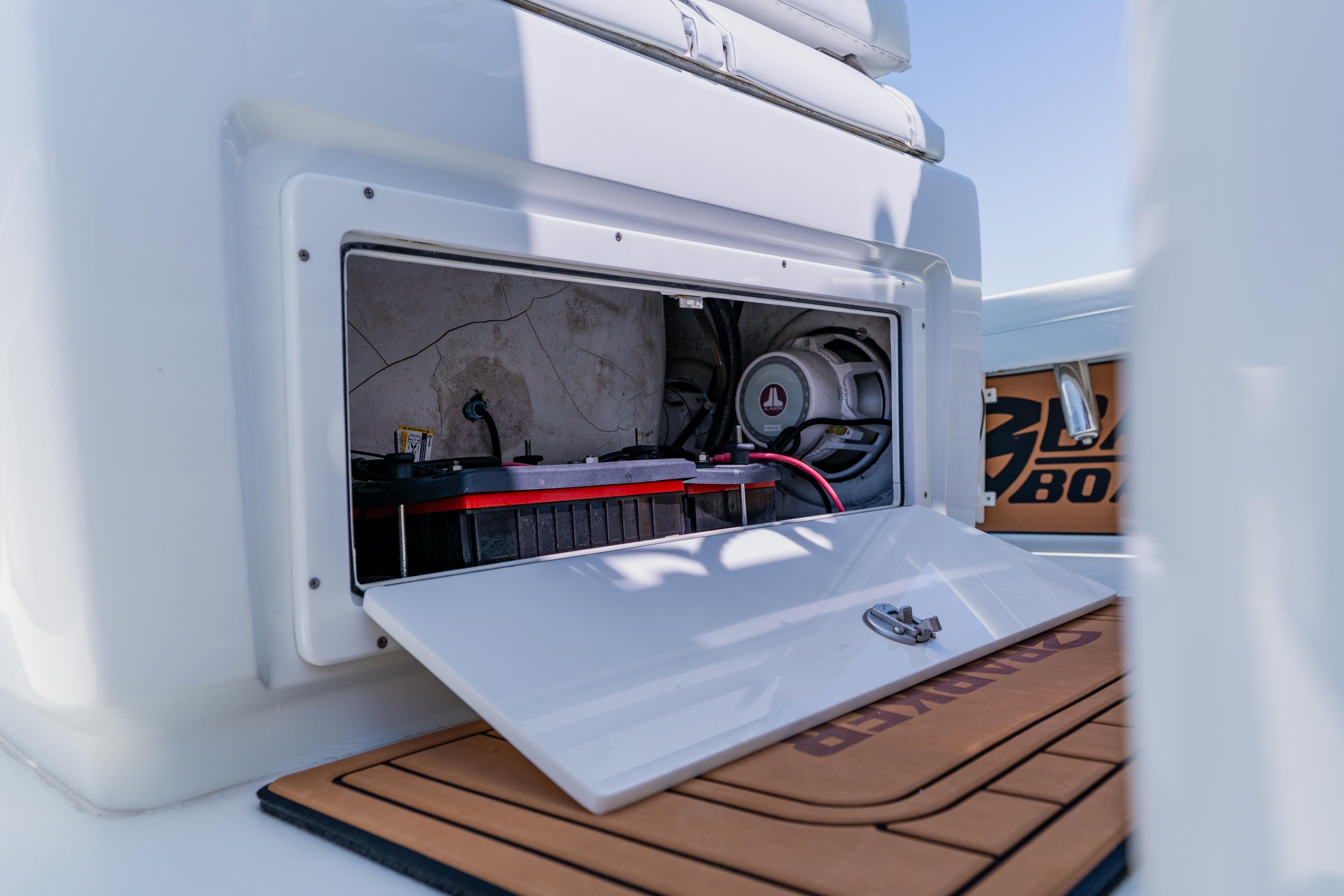 Open storage compartment on 2017 Barker Boatworks 26, revealing battery and wiring.
