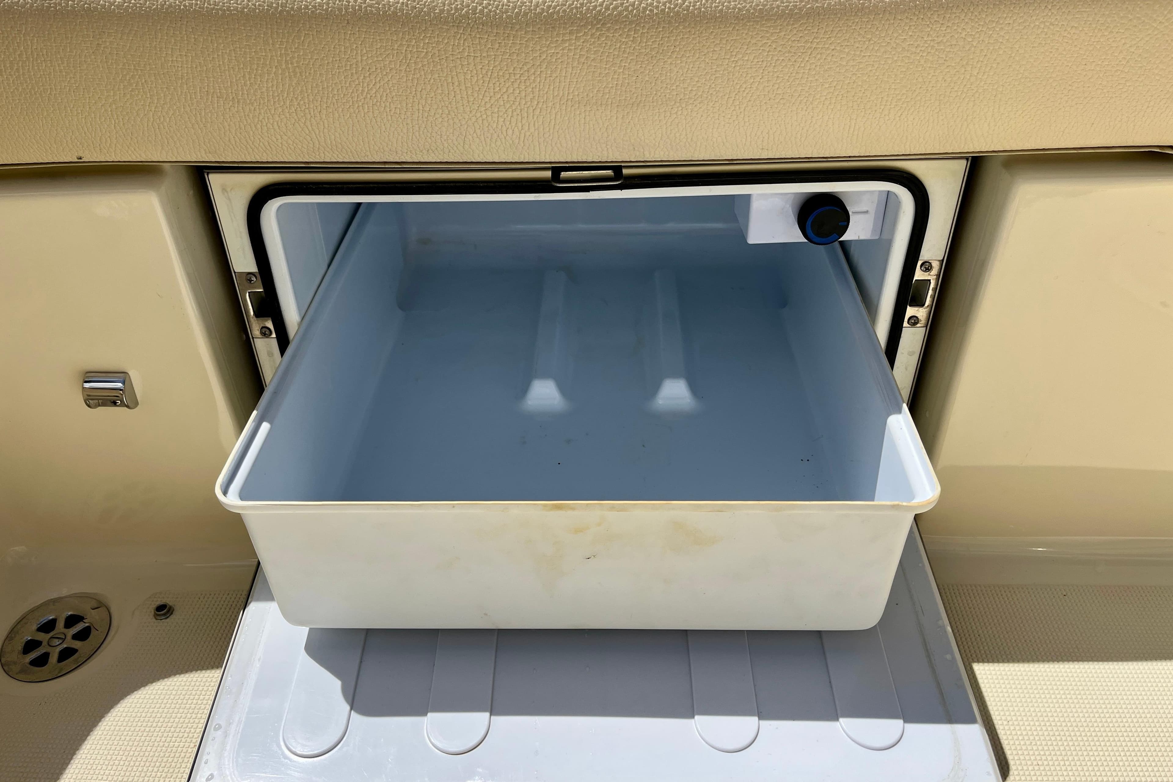 Open storage compartment on 2019 Chris-Craft Launch 27 boat, featuring a white pull-out tray.