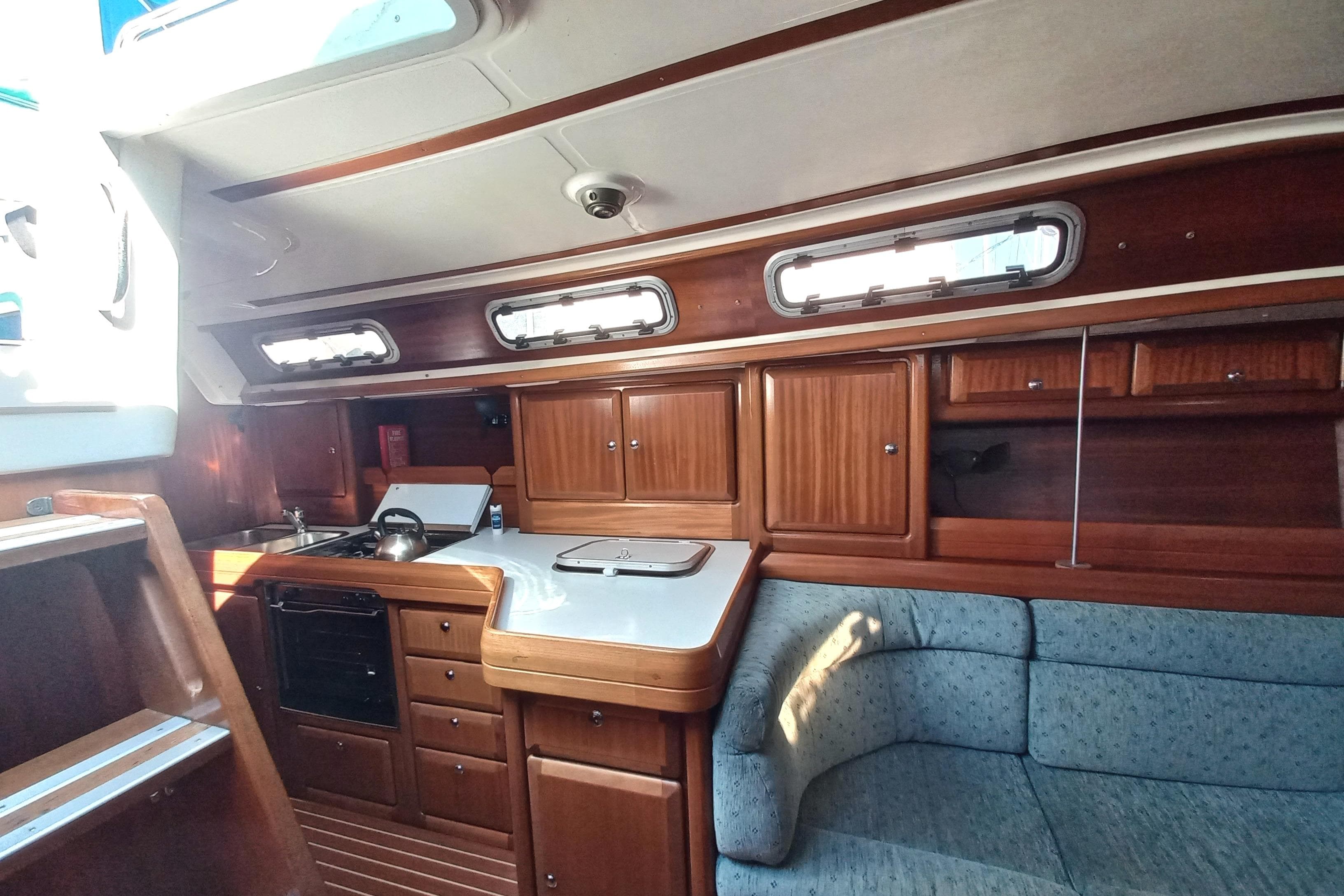 Interior of 1999 Bavaria 38 Ocean yacht with wooden cabinetry and cozy seating area.