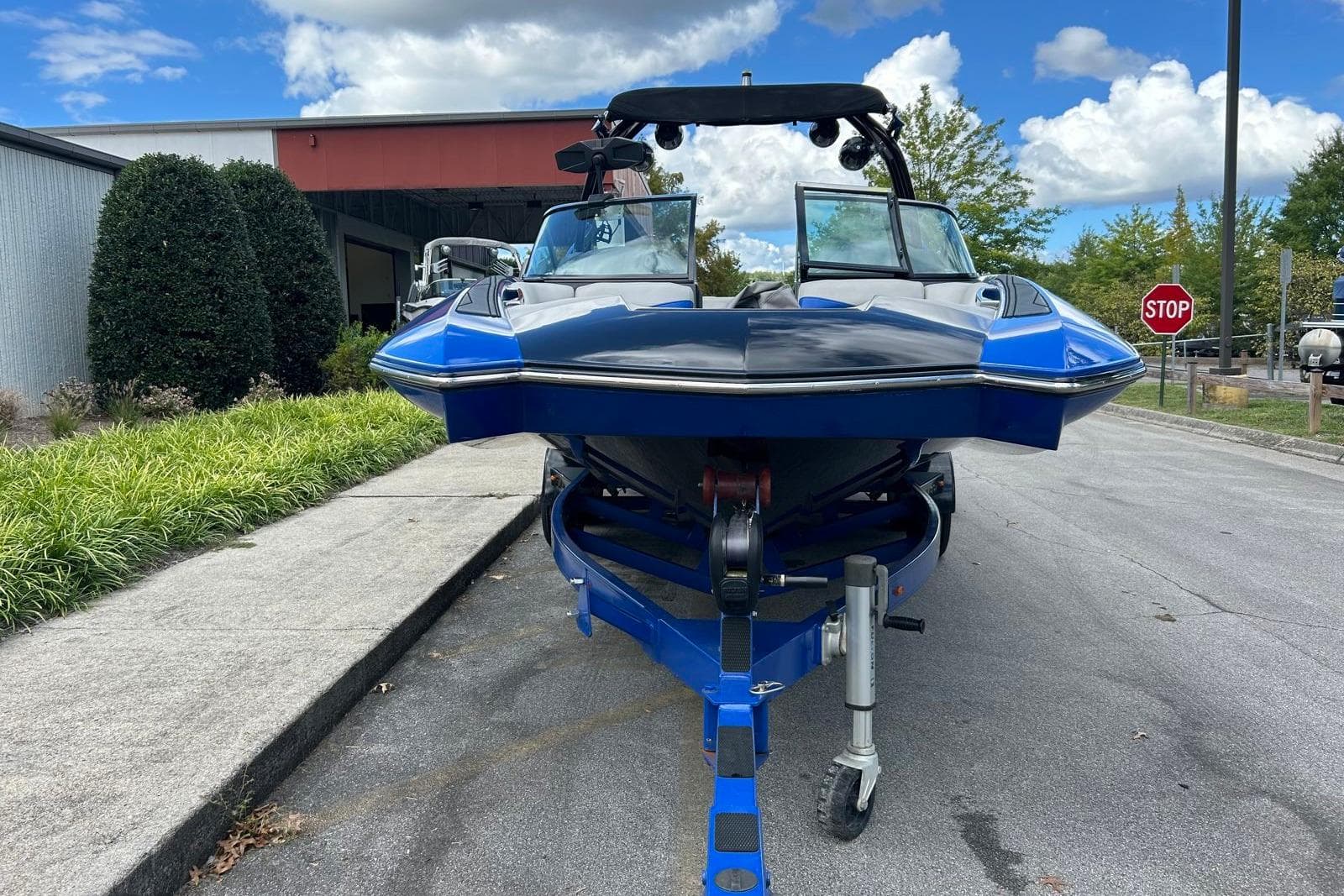 2014 Supra SA 450 boat on trailer, parked outdoors near a building and greenery.