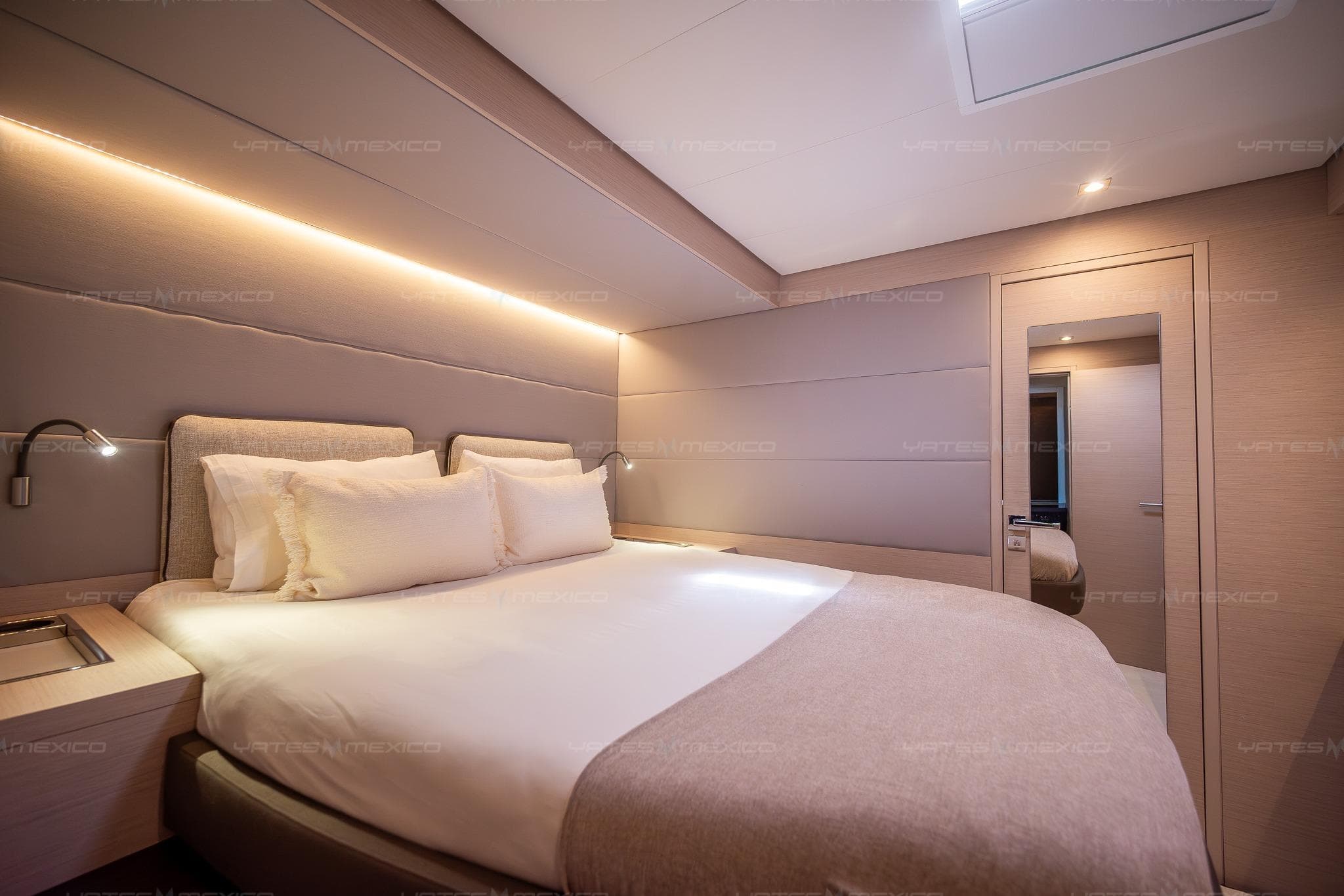 Luxurious bedroom interior of 2023 Lagoon 55 yacht with modern lighting and cozy bedding.