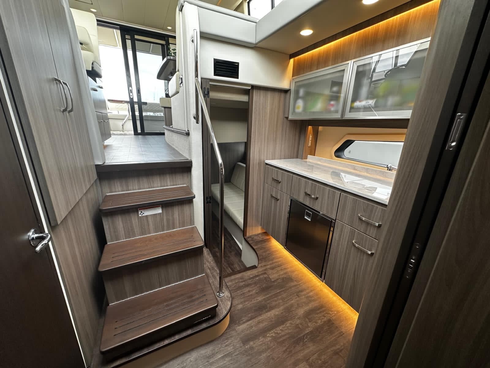 Luxurious interior of 2022 Regal 42 XO yacht with modern kitchen and wooden stairs.
