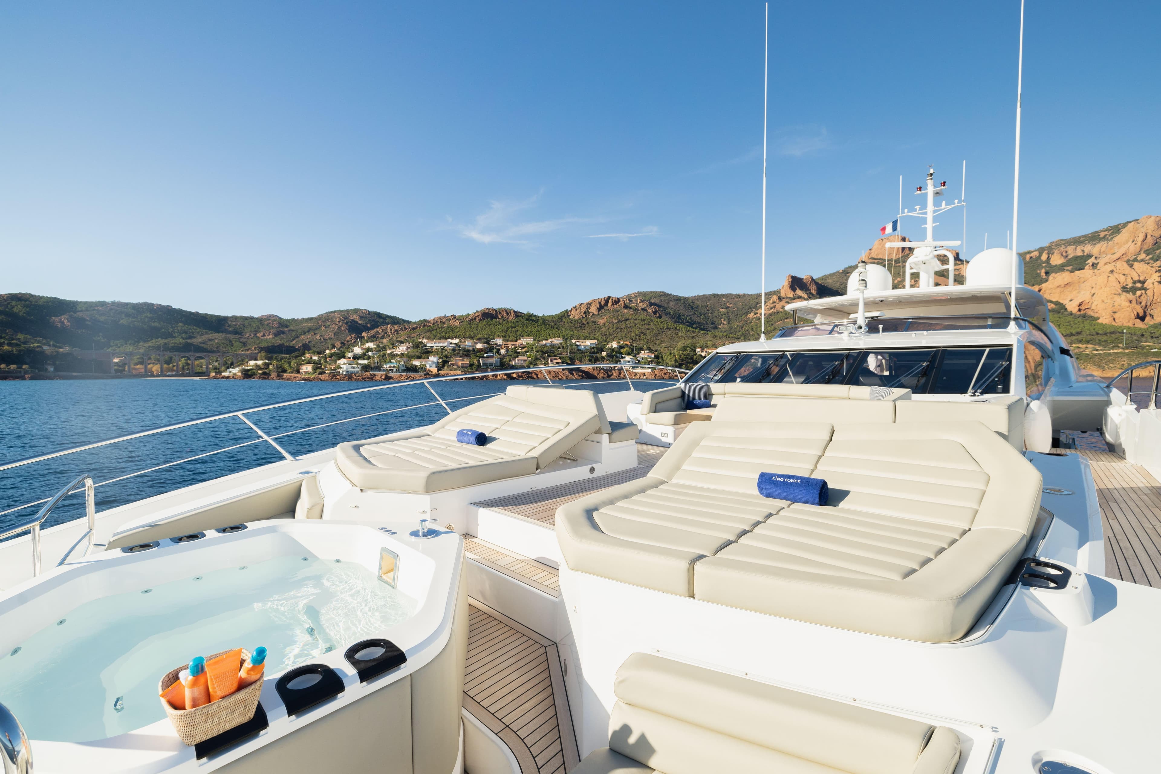 Luxurious 2016 Sunseeker 116 Yacht with sunbeds and jacuzzi, cruising near scenic coastline.