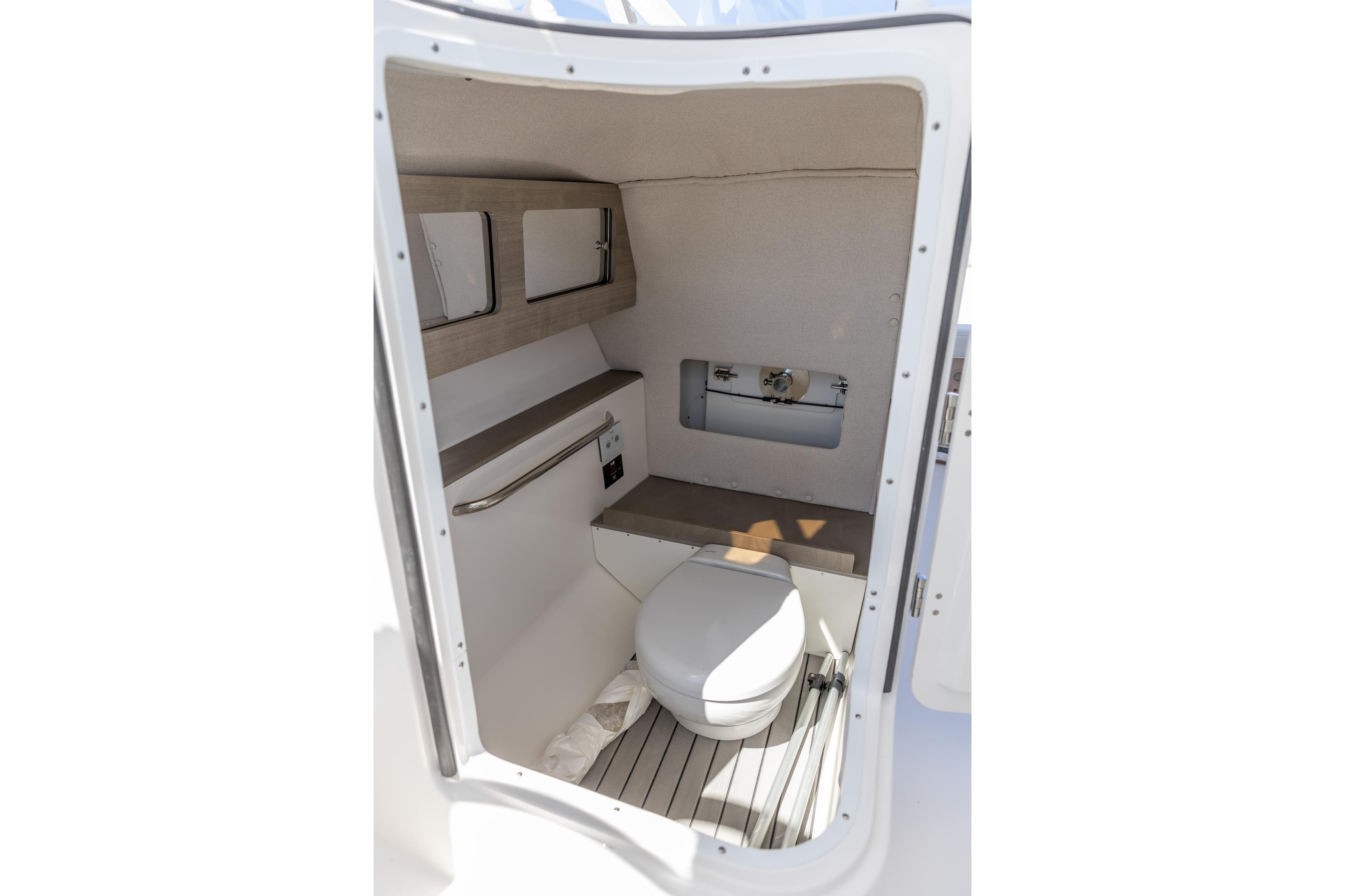 Interior of 2026 Edgewater 248CX Crossover boat, featuring a compact marine toilet.