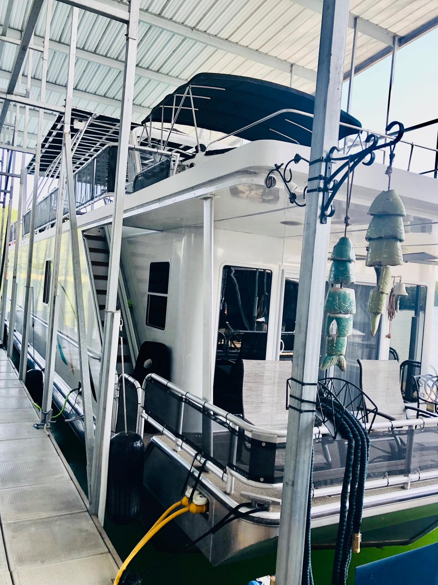 2016 Thoroughbred 67x17 houseboat docked under covered marina.