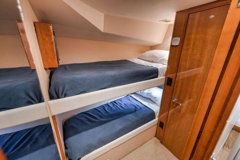Interior of 2009 Hatteras 60GT yacht with cozy bunk beds and wooden finishes.