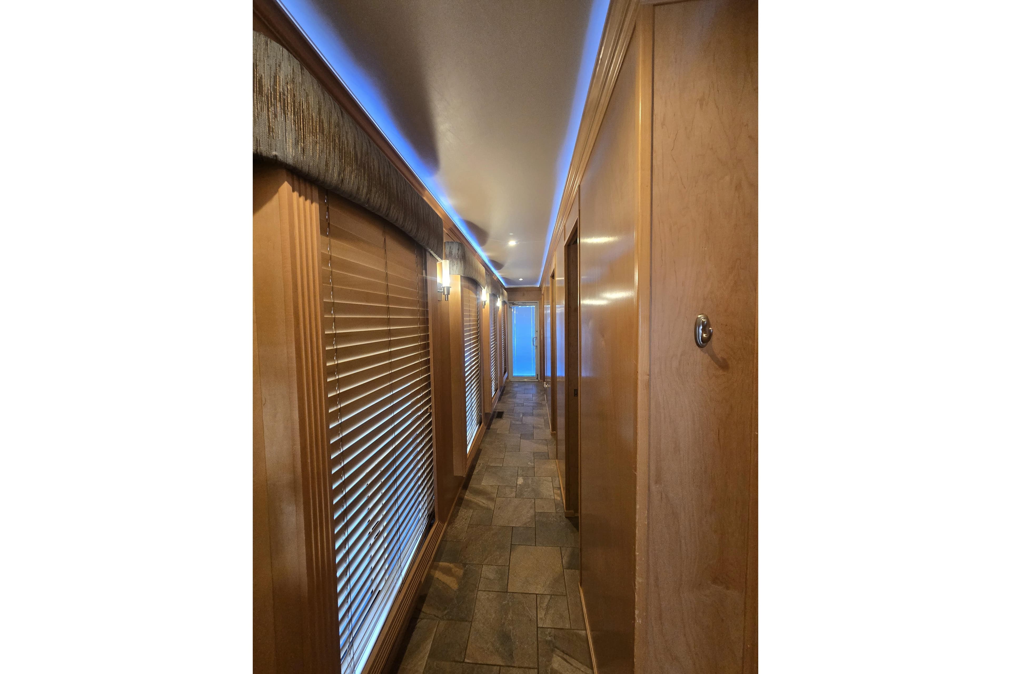Luxurious Thoroughbred 80'x 18' 2013 model interior hallway with wood paneling and ambient lighting.