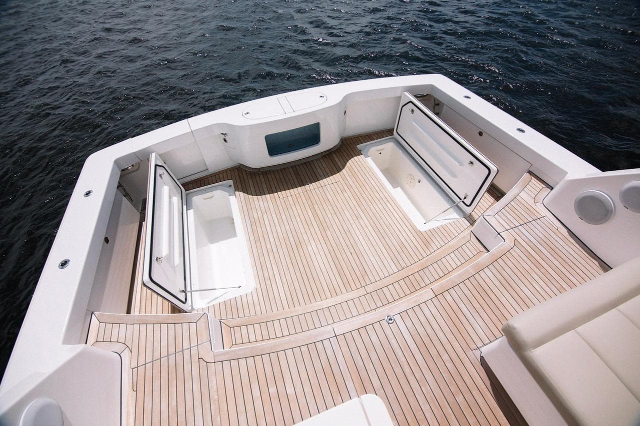Manufacturer Provided Image: Bertram 50 Sport 2026 boat deck with open storage compartments, on calm water.