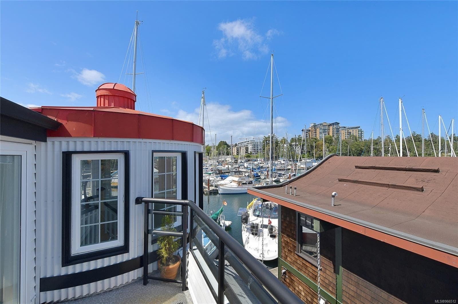 Custom 2005 float home with marina view, featuring boats and clear blue sky.