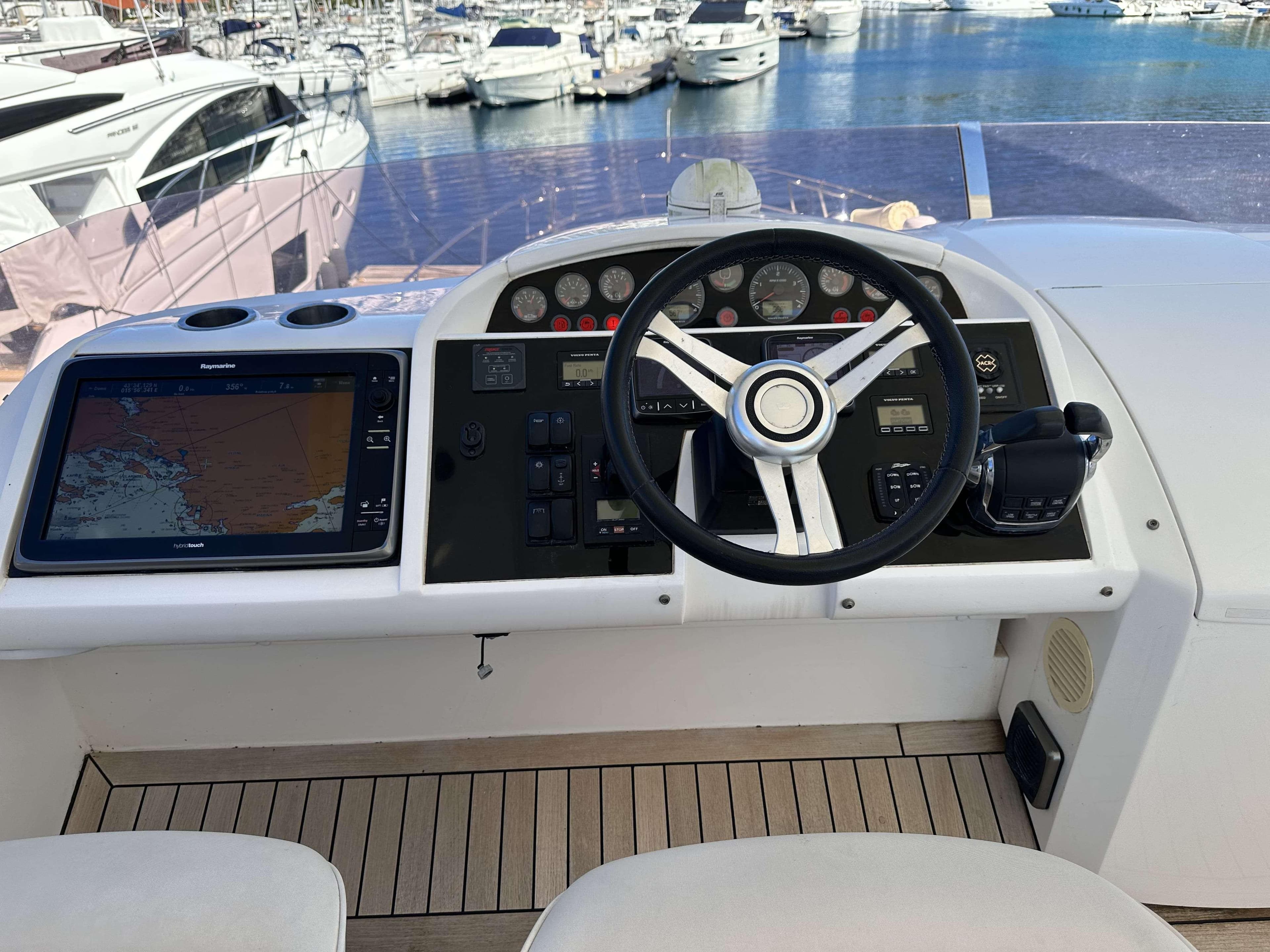 Control panel of a 2014 Princess 60 yacht with navigation equipment and steering wheel.