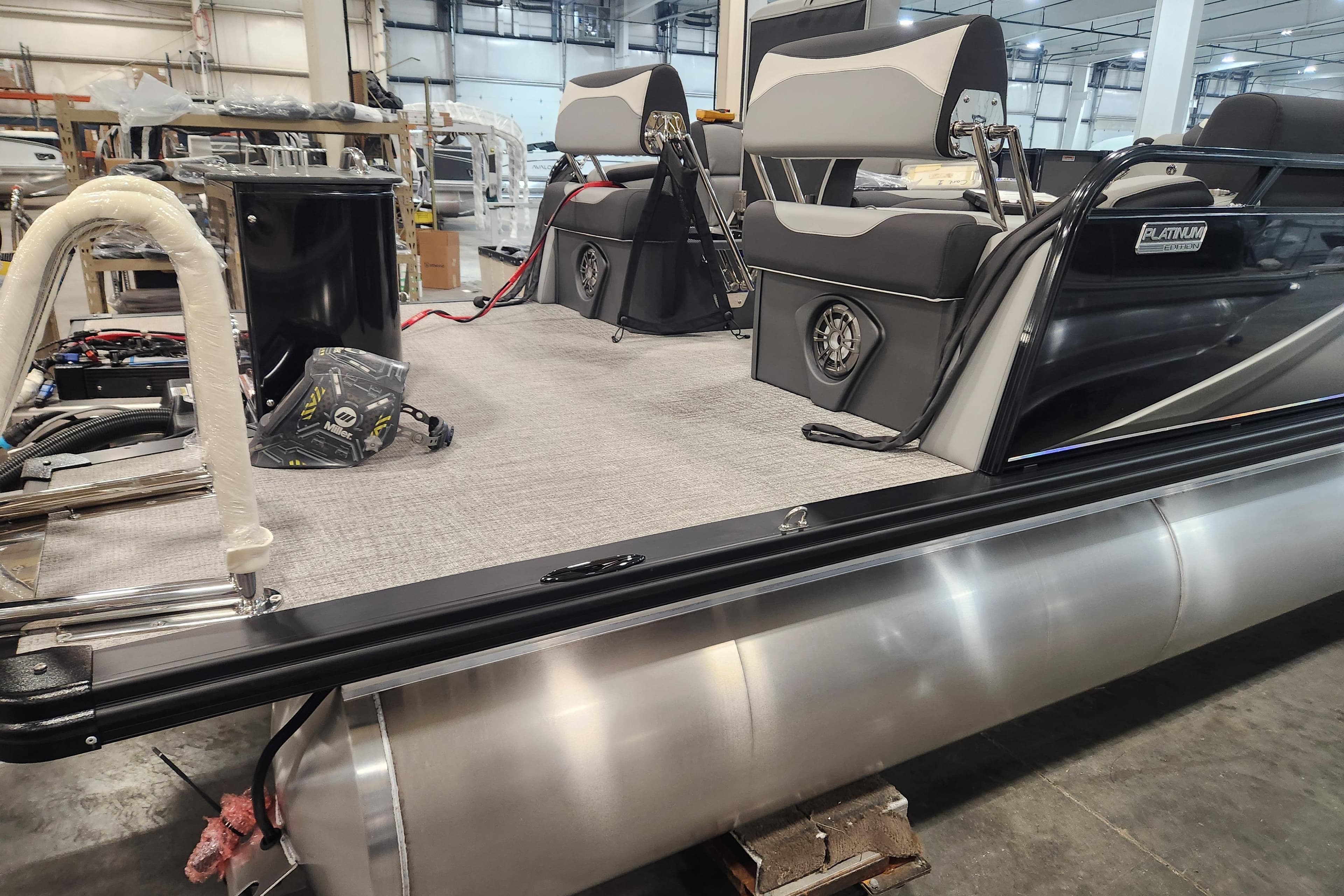 2026 Tahoe Pontoon 23 LTZ Quad Lounge interior, showcasing seating and deck details in a warehouse.