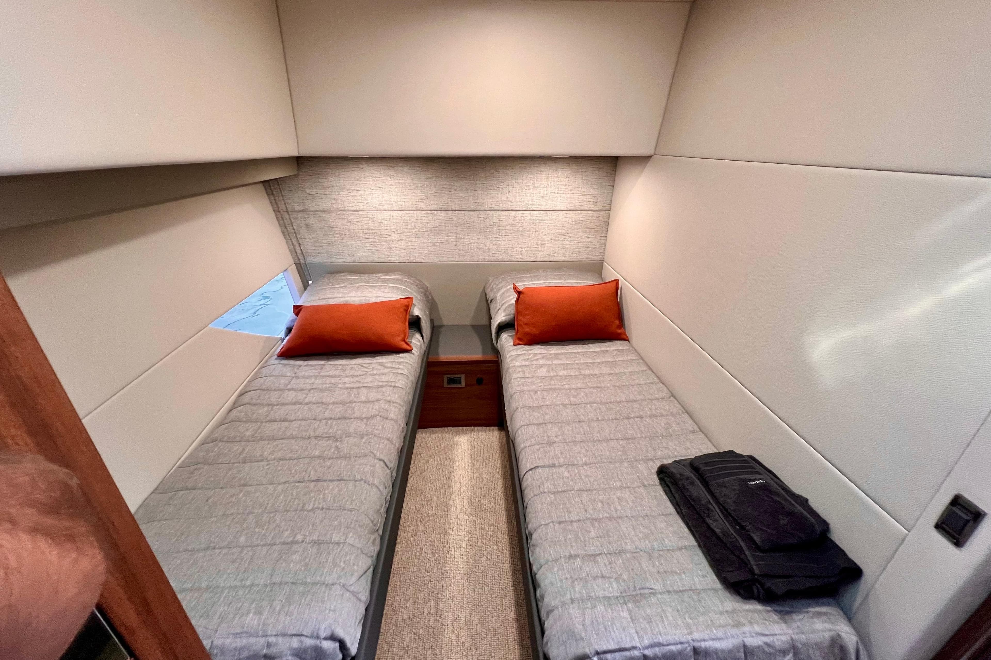 2023 Maritimo M600 yacht cabin with twin beds, gray bedding, and orange pillows.
