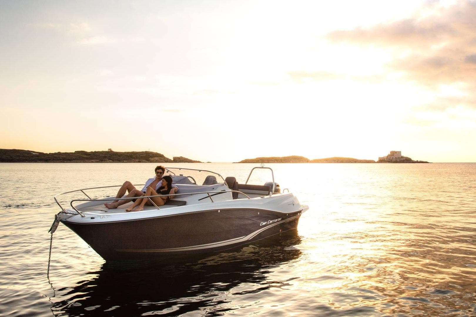 2026 Jeanneau Cap Camarat 6.5 WA boat at sunset with two people relaxing onboard.