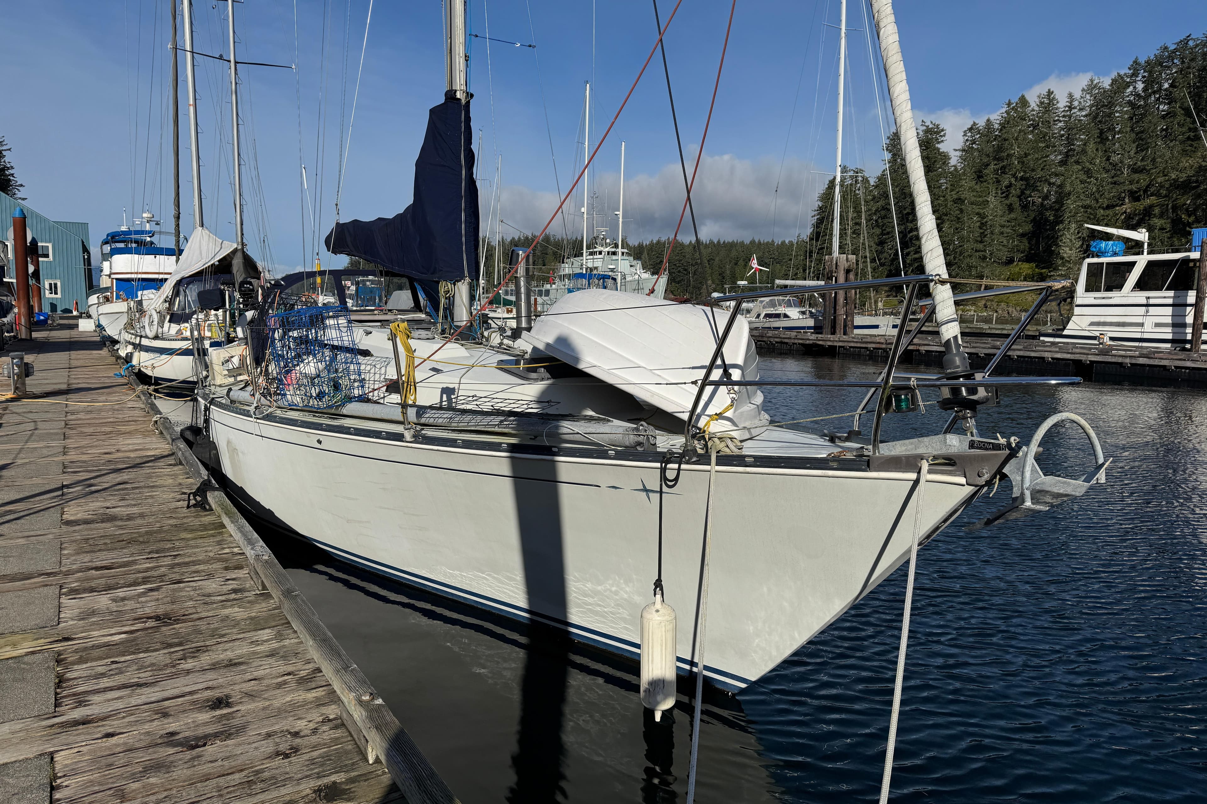 1982 C&C 37 sailboat docked at a marina, surrounded by other boats and trees.