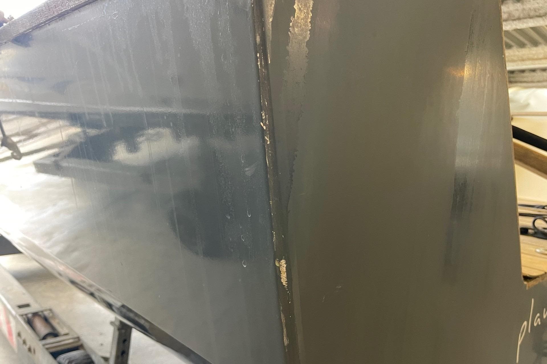 Close-up of a 2015 Chantier des Ileaux X.0 boat hull in a workshop.