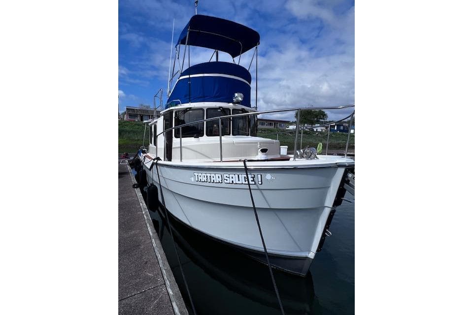 2021 Ranger Tugs R-31 CB boat docked with blue canopy under a cloudy sky.