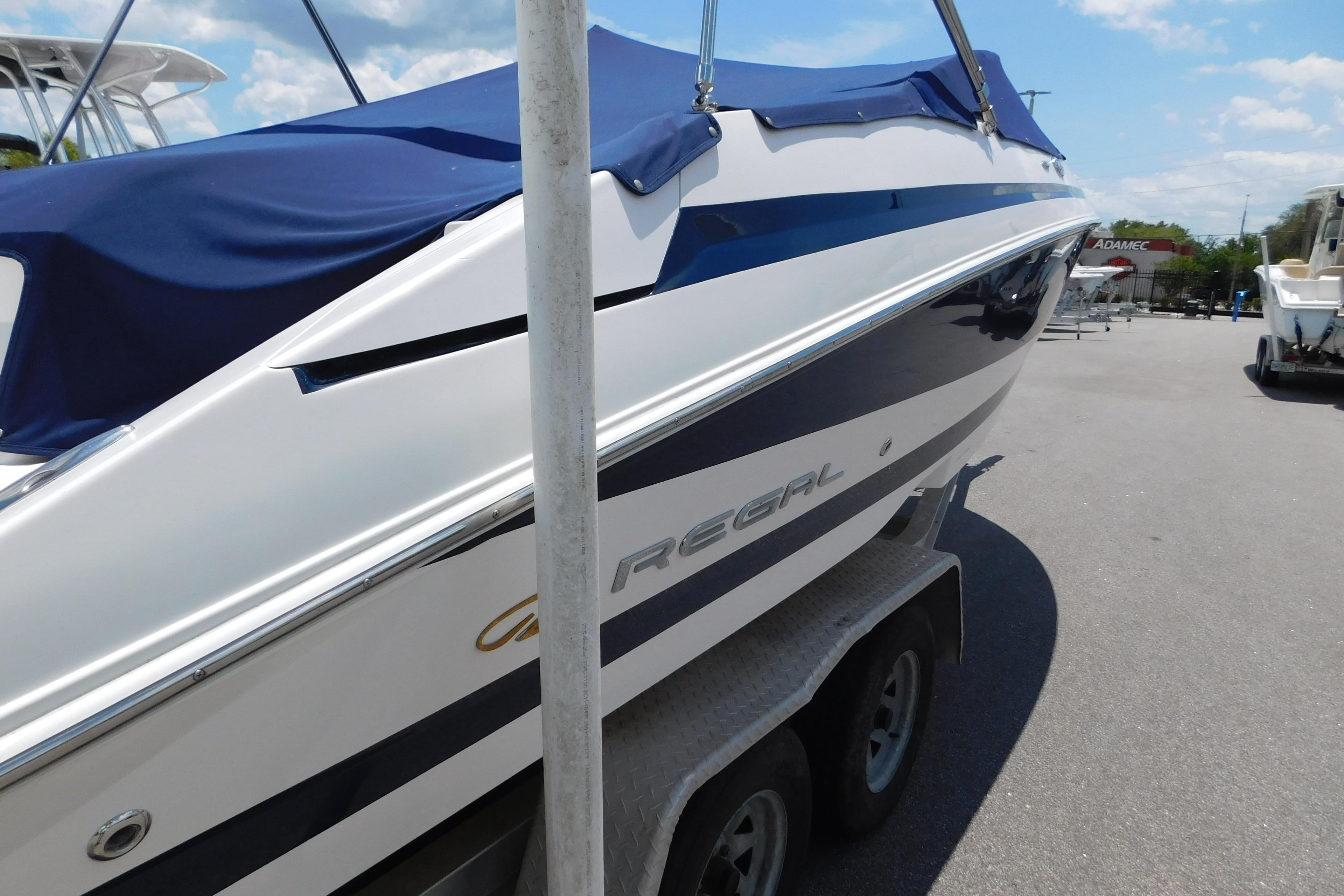 2004 Regal 2250 LSC boat with blue cover on trailer, parked outdoors.