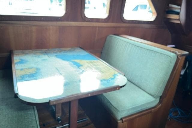 Pilothouse interior of 2020 Bruce Roberts 46, featuring a map-covered table and cushioned seating.