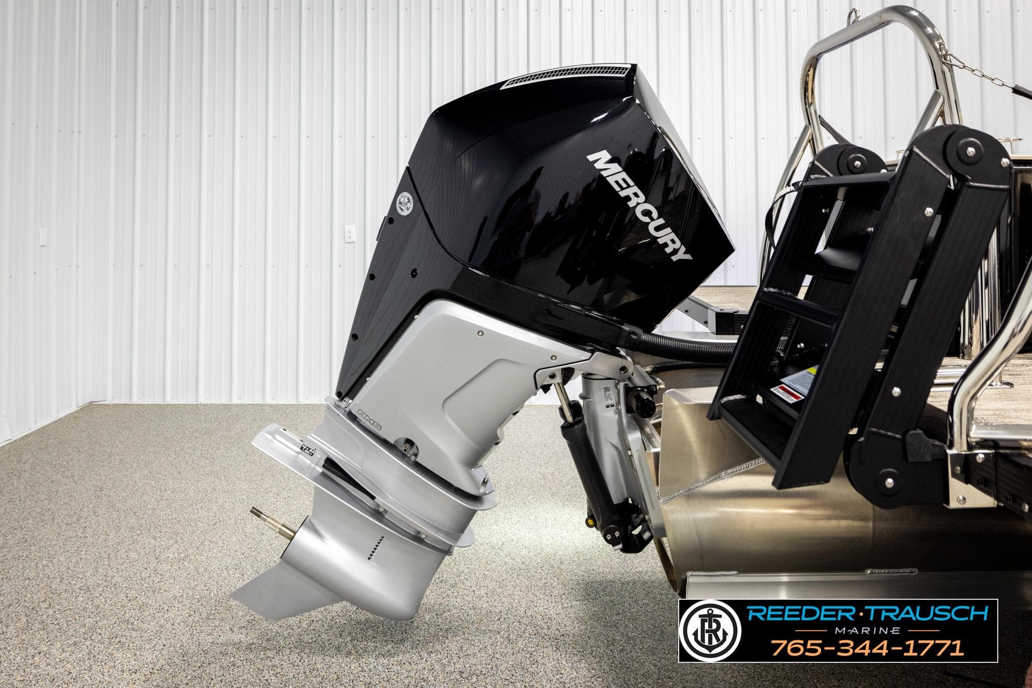 Outboard motor on Avalon CAT QLS 2026 boat, displayed indoors with ladder and branding.
