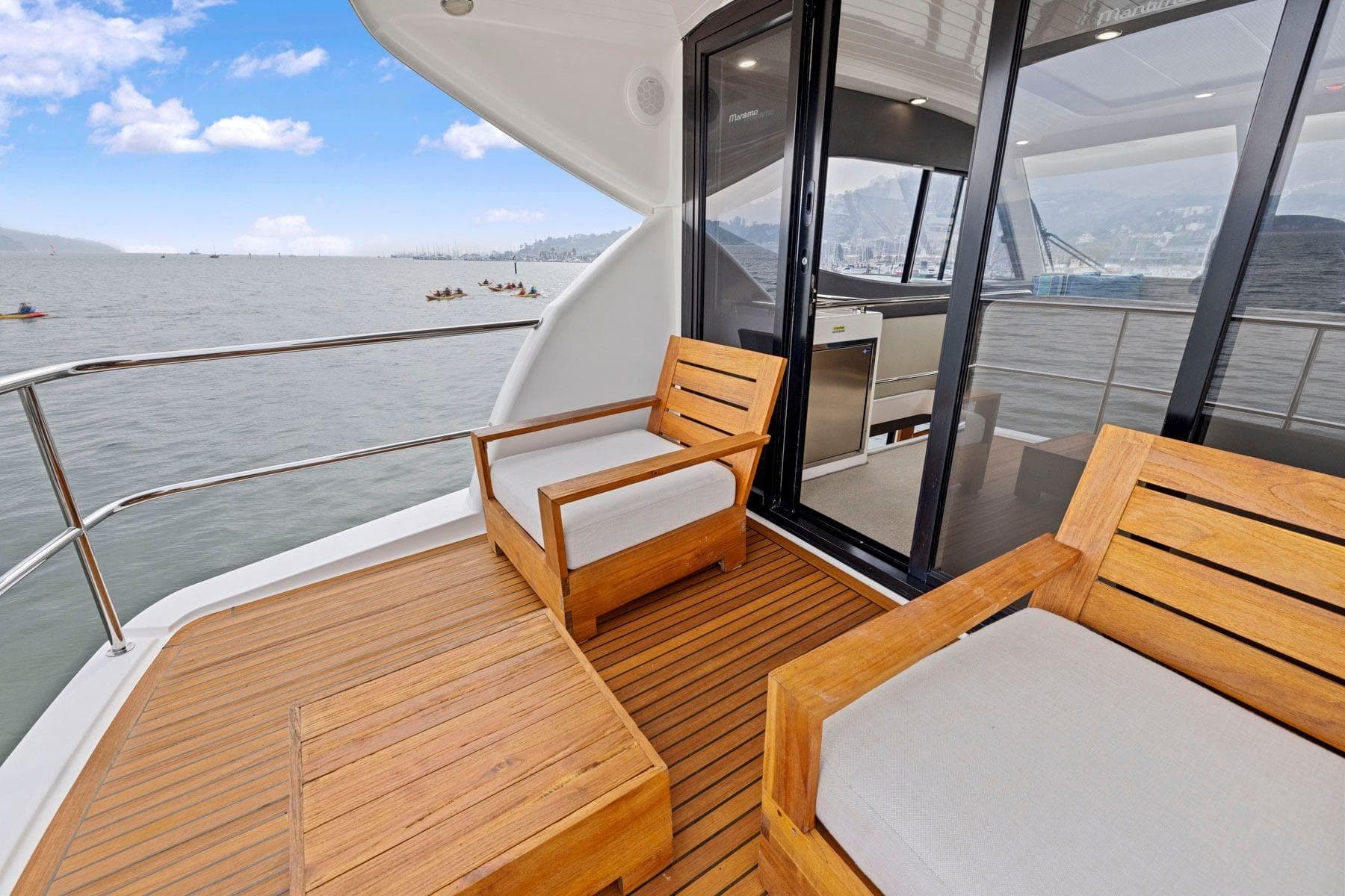 Luxury Maritimo M50 yacht deck with wooden seating, ocean view, and sliding glass doors.