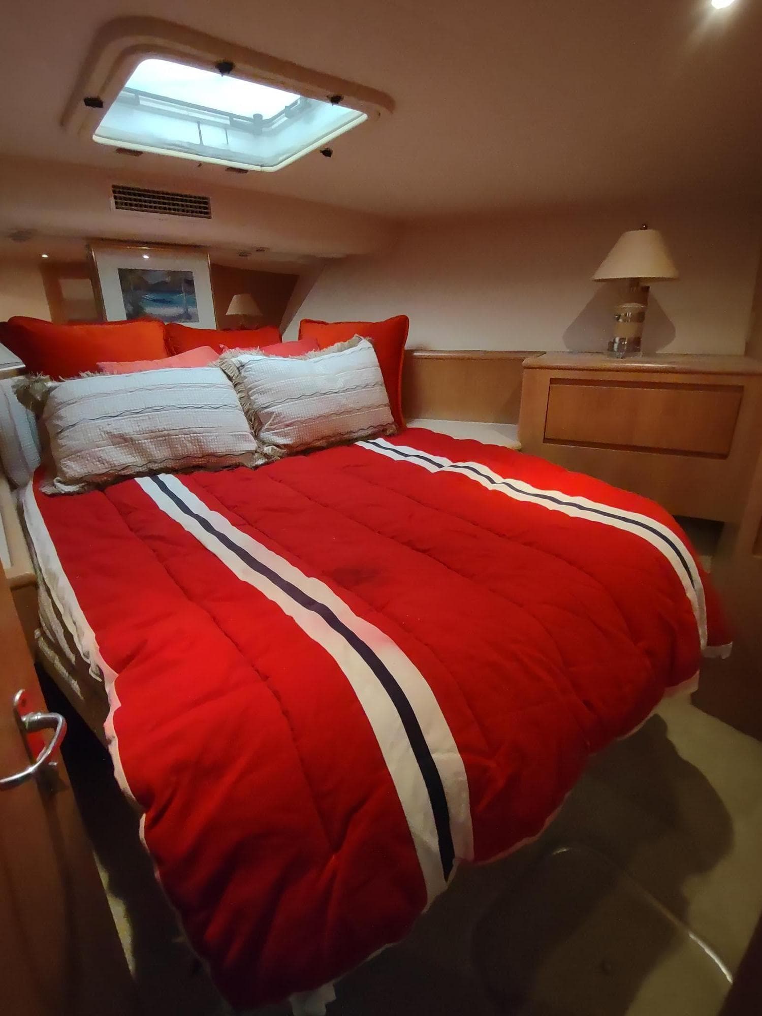 Cozy bedroom with red bedding in a 1996 Hatteras 50' Sport Deck yacht.