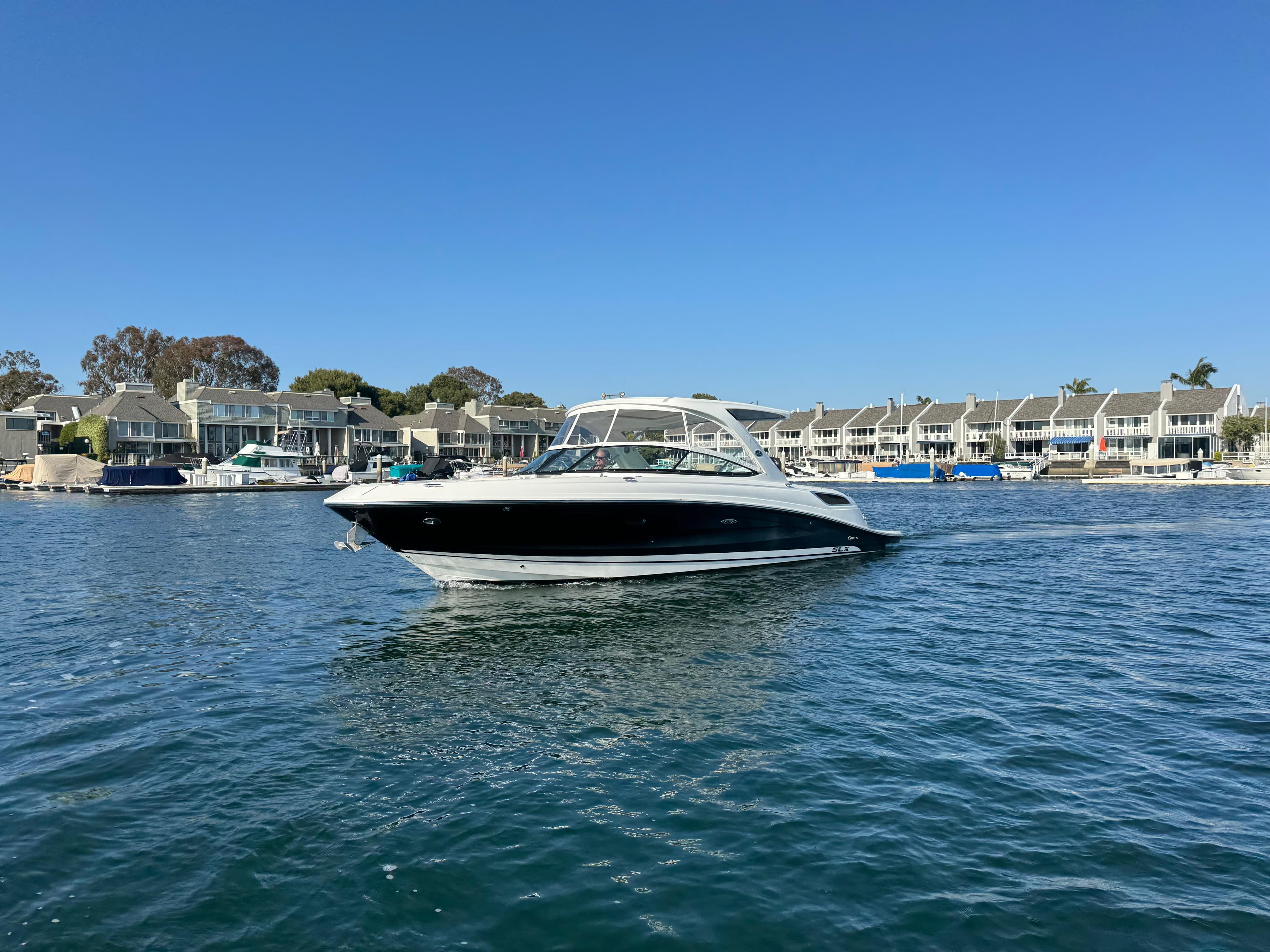 2015 Sea Ray SLX 350 boat on calm water near coastal homes.