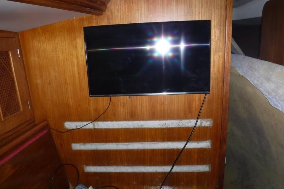 Interior of 1986 Fast Masthead Sloop with mounted TV on wooden wall.