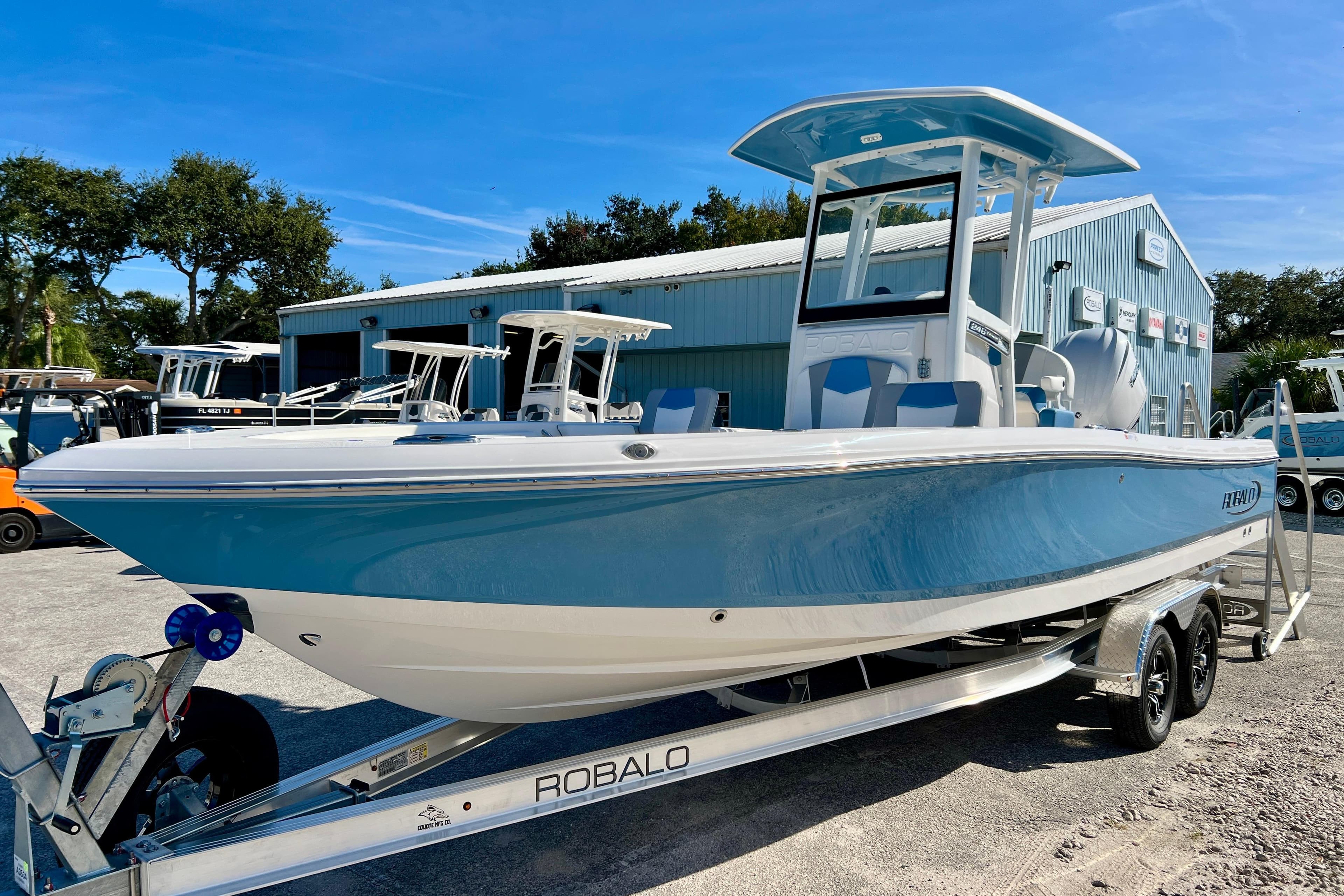 2026 Robalo 246 Cayman boat on trailer, blue and white, parked outdoors.